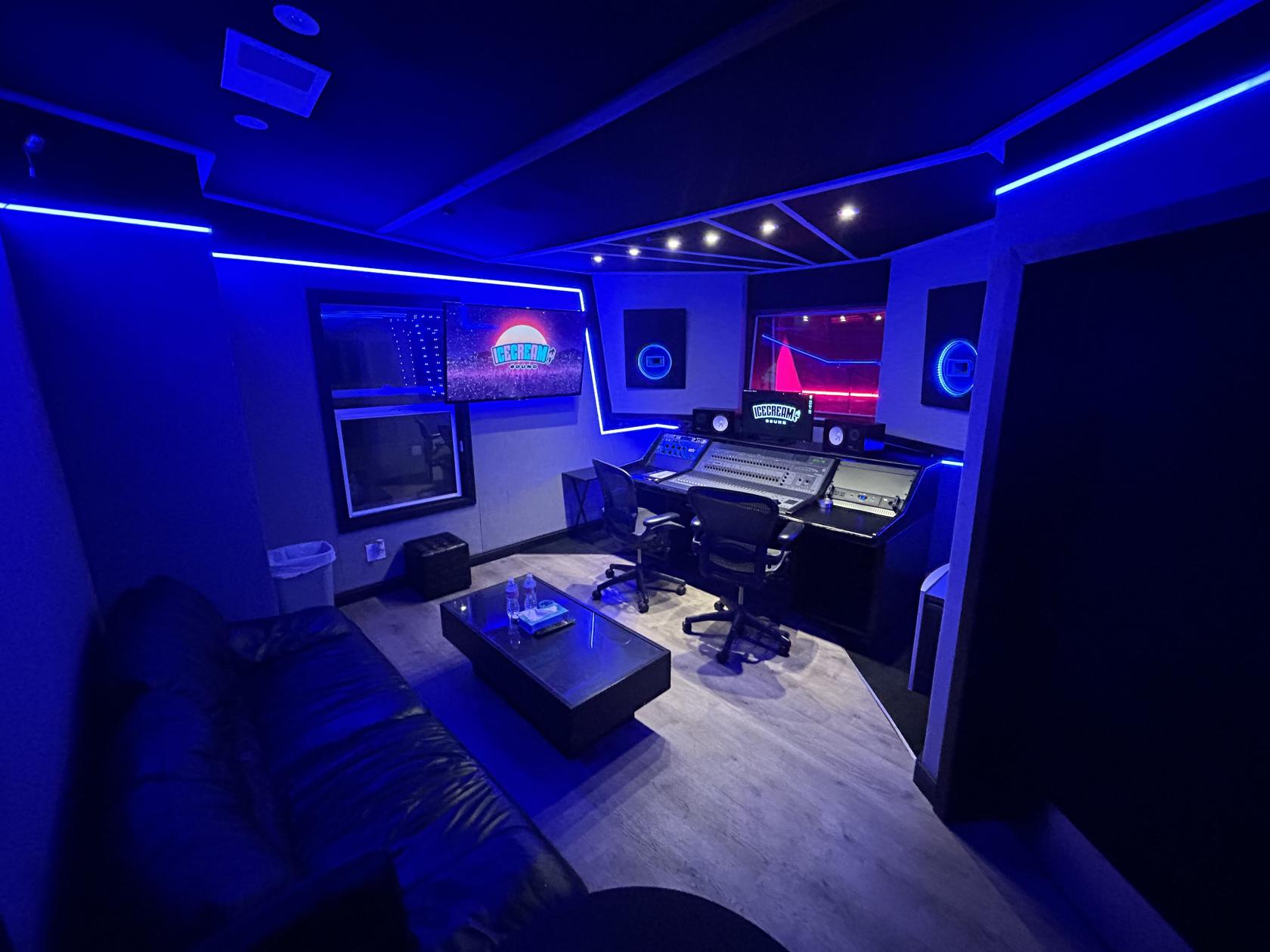 A recording studio with LED accent lighting, soundproof walls, a mixing desk, and a lounge area at Ice Cream Sound Studios.