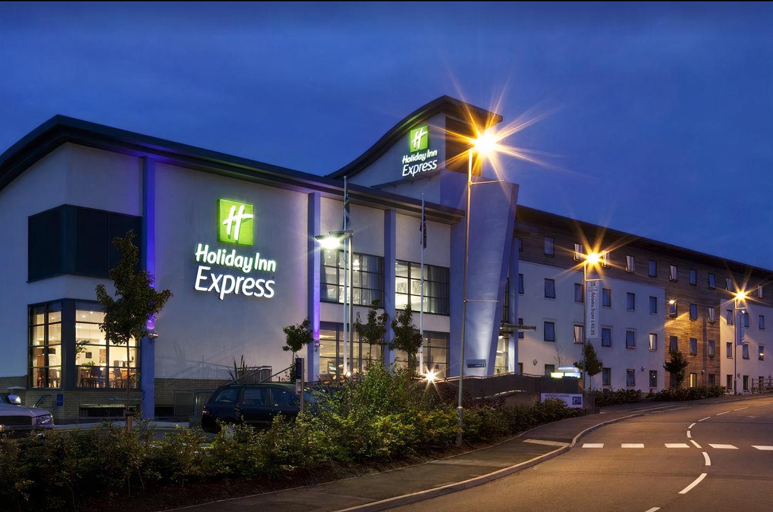 A hotel with illuminated signage, modern exterior architecture, and street lighting at Holiday Inn Express Walsall.