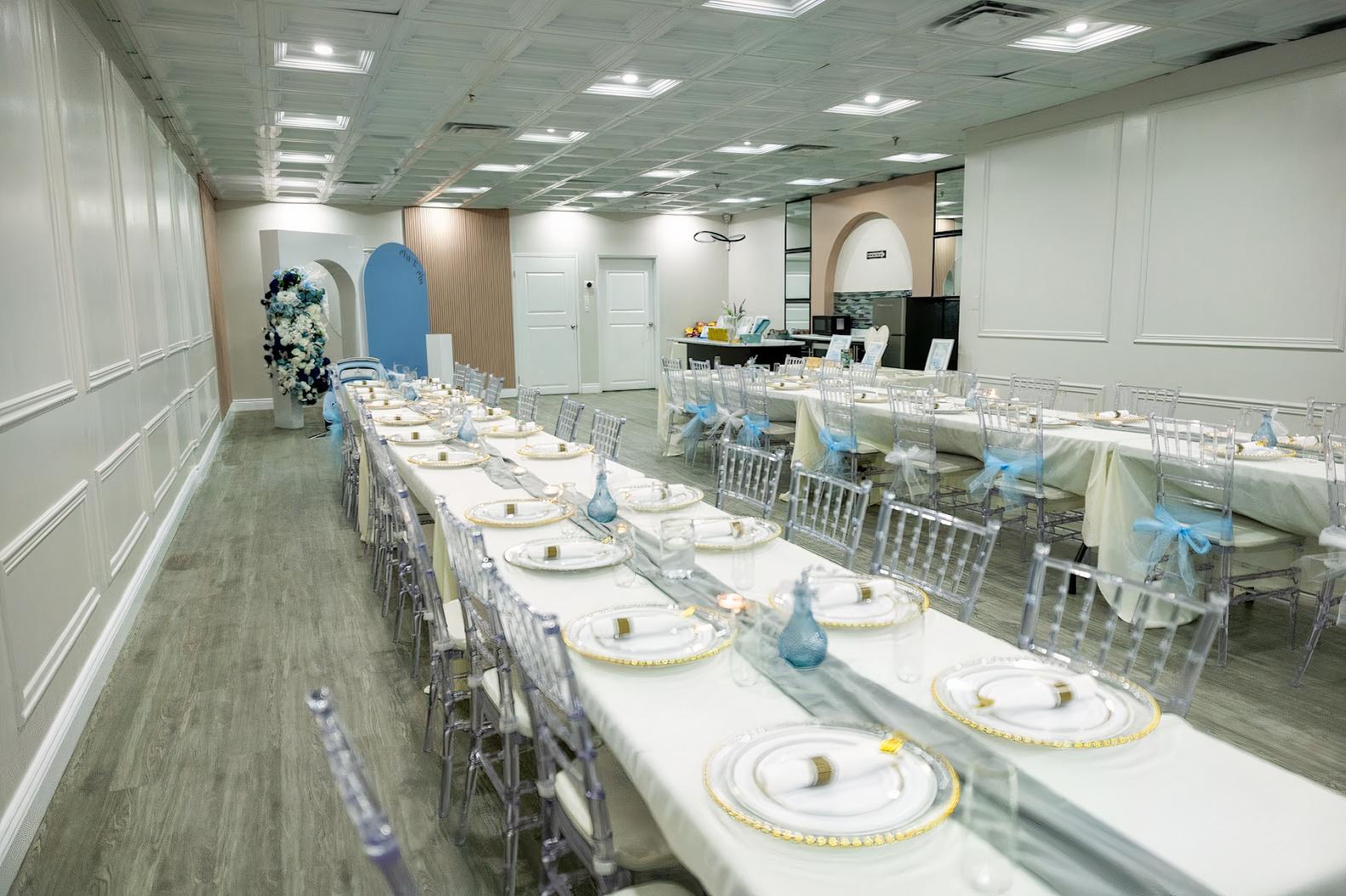 An event venue with long banquet tables set with white linens, clear chairs, and decorative blue accents at Marquee Studios.
