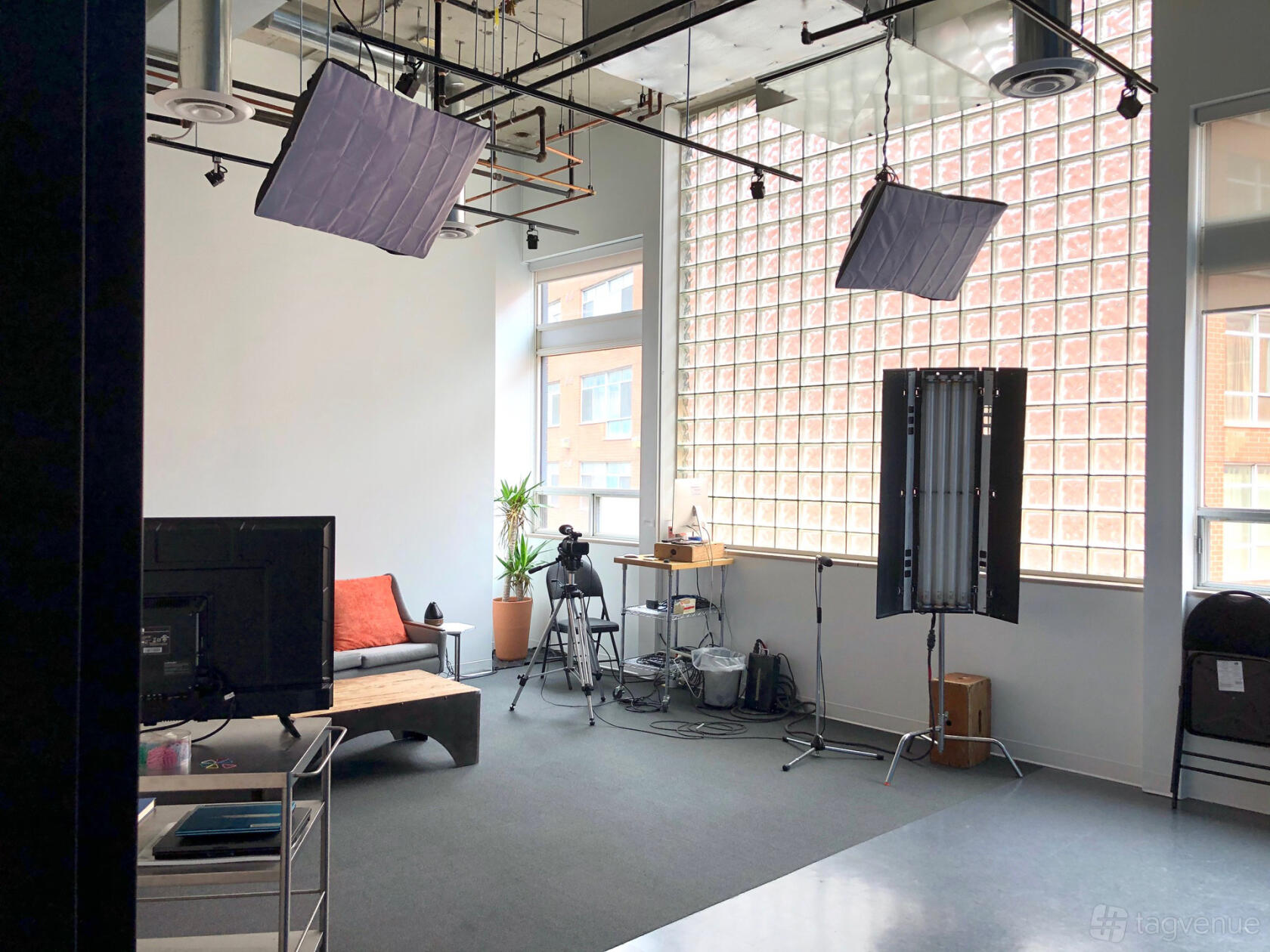 A photo studio with large windows, professional lighting equipment, and a small seating area at Powerhouse Casting.