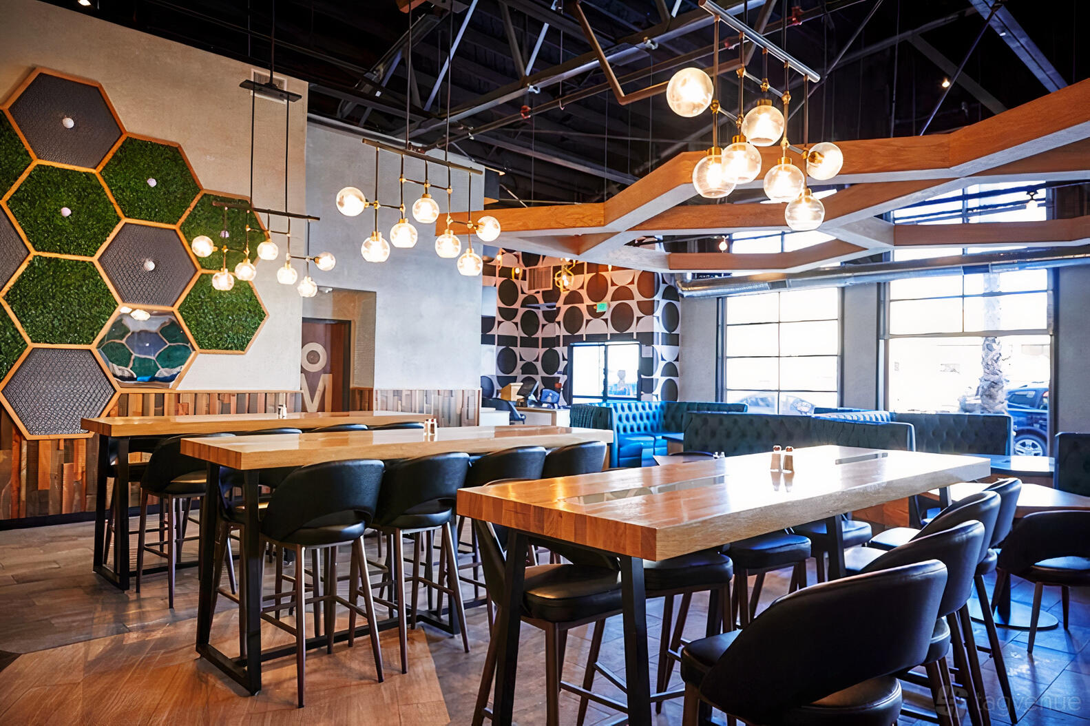 An event space in a restaurant with wooden tables, black chairs, globe pendant lights, and geometric wall decor at Break Point.
