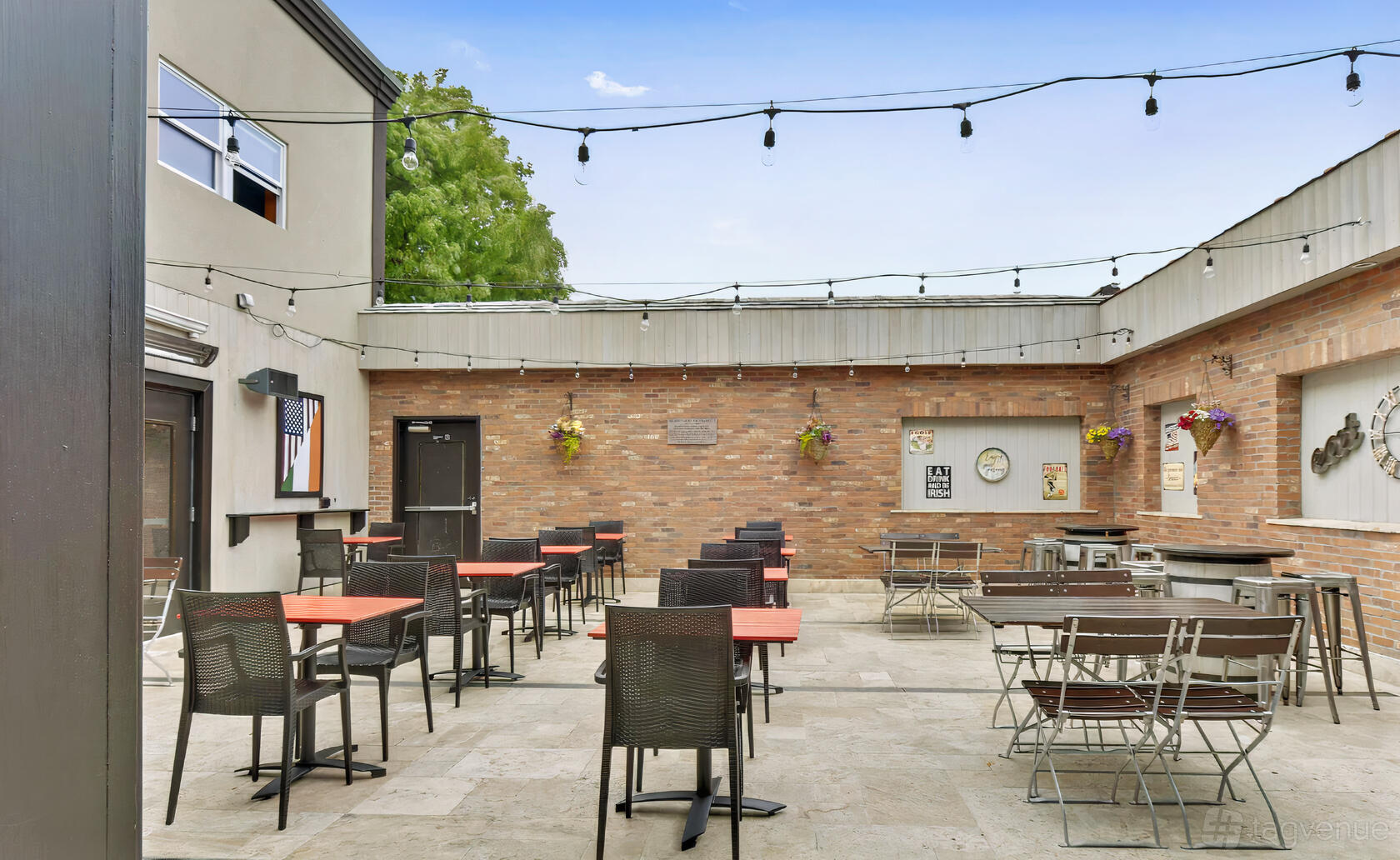 An outdoor restaurant patio with brick walls, hanging lights, and red tables at Mickey Spillane's.