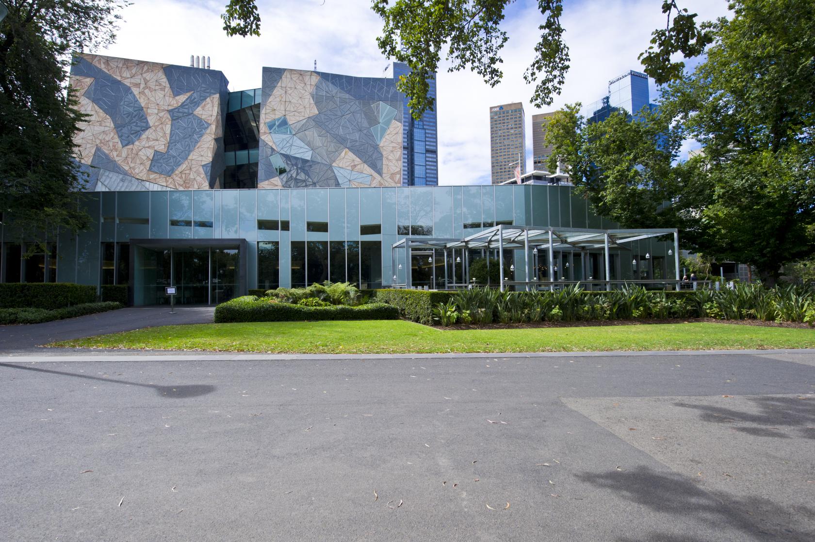 A versatile event space with glass exterior walls, geometric facade, and surrounding greenery at Zinc at Fed Square.