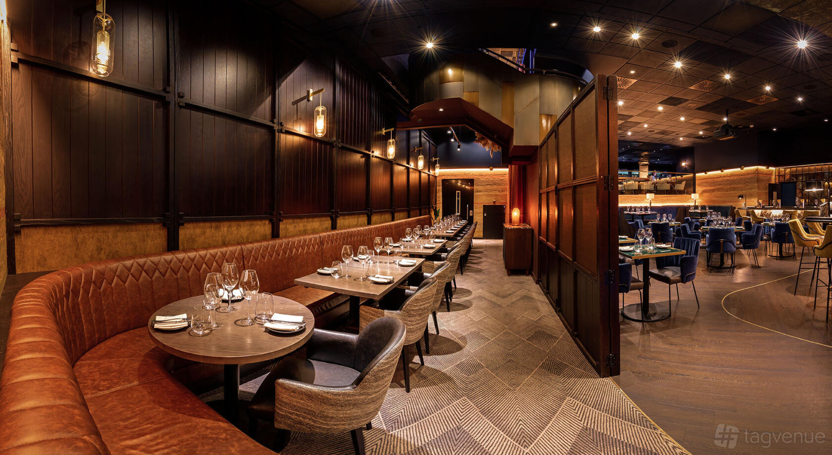 A dining room with tufted leather banquette seating, dark wood tables, and ambient wall lights at Gaucho Charlotte Street.