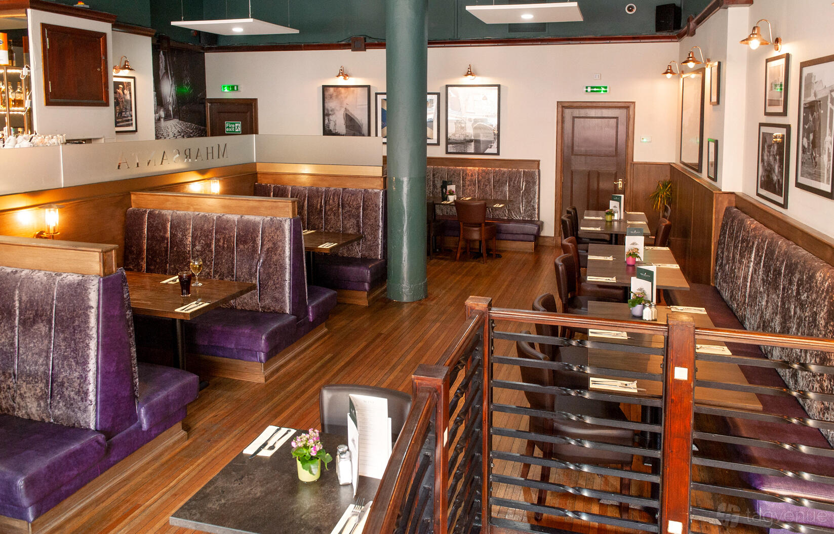 An event space in a restaurant with purple velvet booths, wood accents, and framed wall art at Mharsanta Restaurant & Bar.