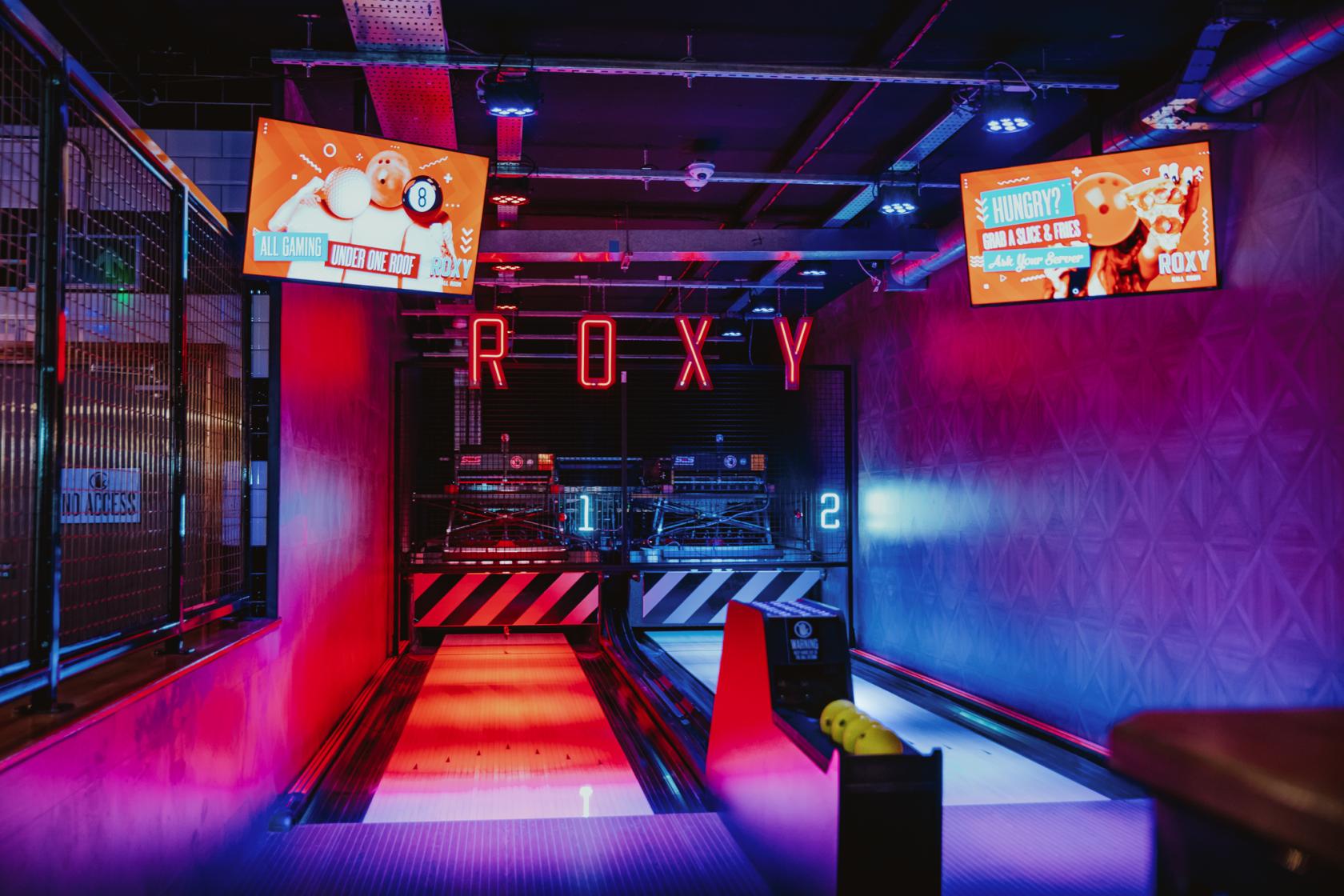An event space with neon lighting, bowling lanes, and digital scoreboards at Roxy Ball Room Victoria Square.