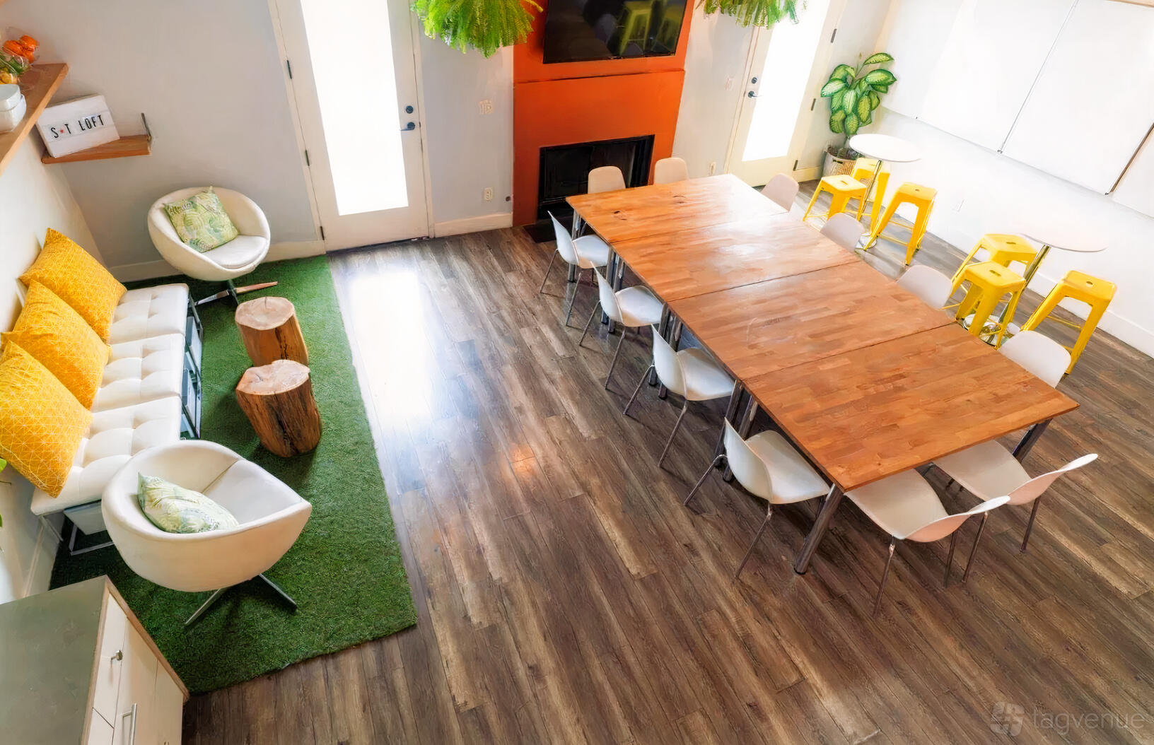 A loft meeting space with wooden floors, large windows, a long wooden table, and lounge seating at Boutique Event & Meeting Loft.