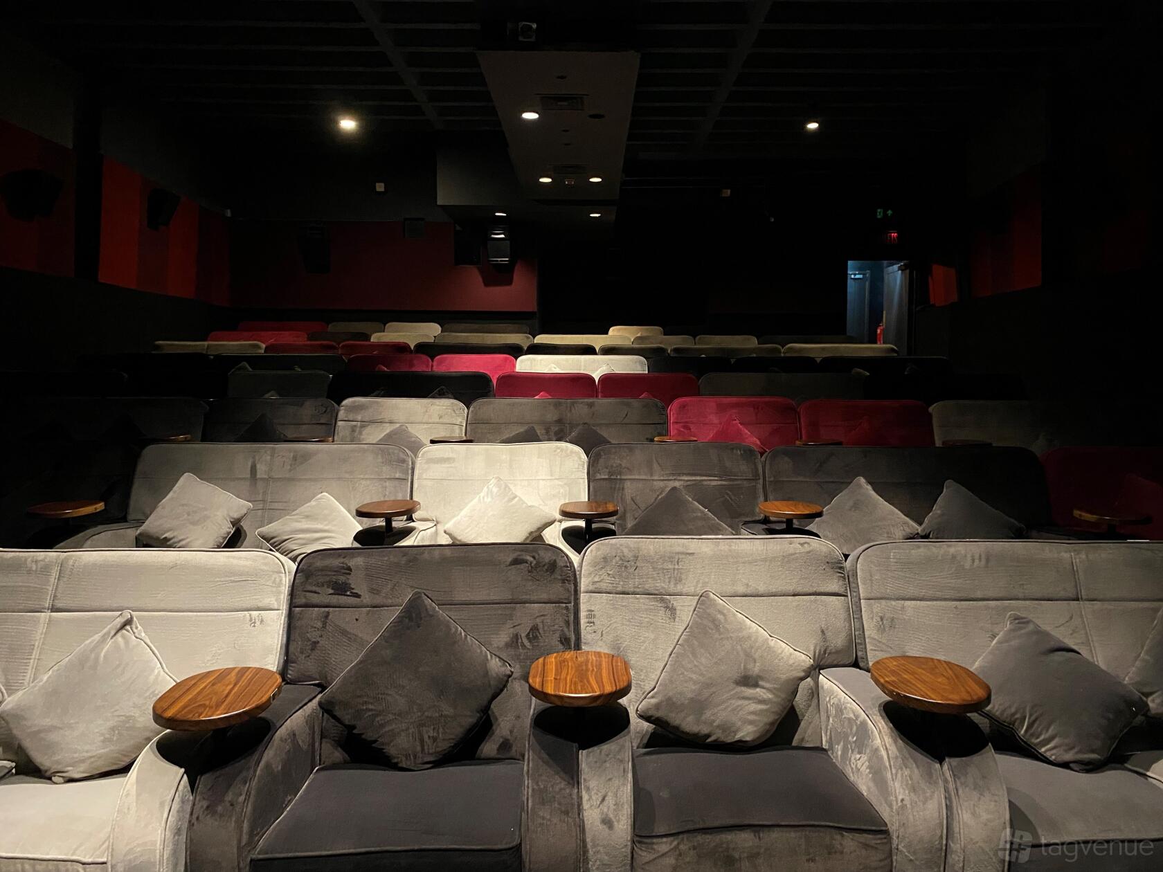 An event space in a cinema with plush sofas, scatter cushions, and individual wooden side tables at Everyman Walton.