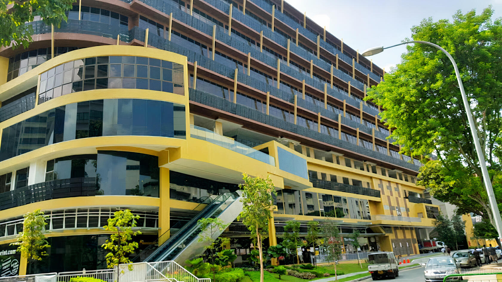 A multi-story meeting centre with large glass windows and yellow exterior accents at Training Room at The Commerze.