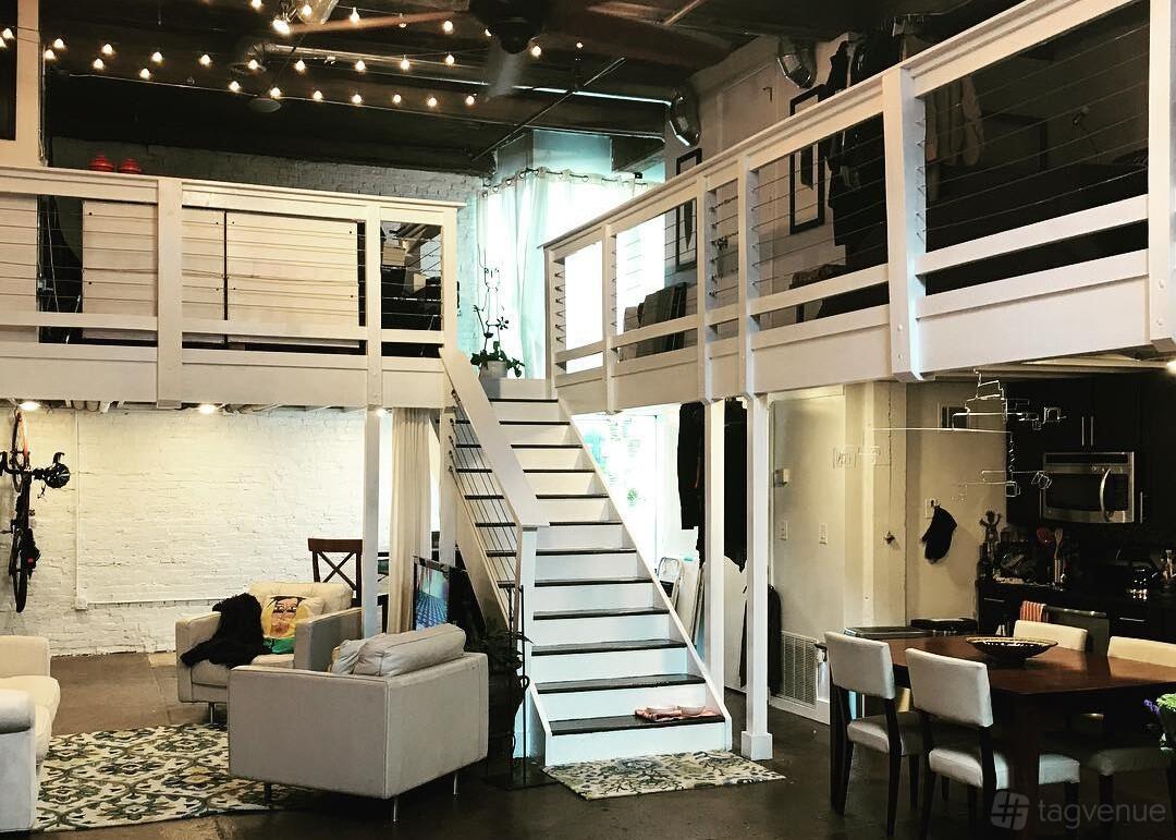 An event venue with a loft area, white stairway, exposed ductwork, and string lights at Lorikay Photography.