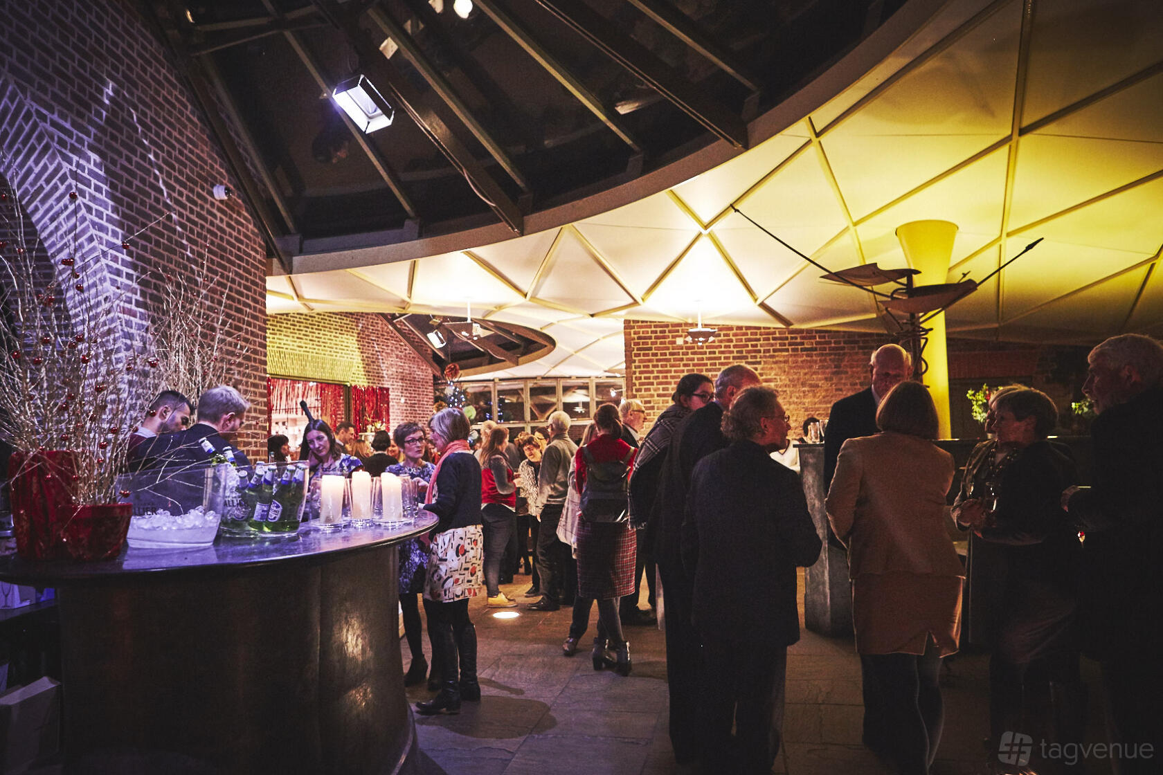 An event space with exposed brick walls, glass ceiling panels, and atmospheric lighting at Museum of the Home.