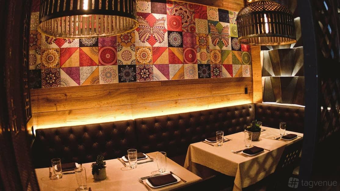 An intimate restaurant event space with colorful patterned wall art, upholstered seating, and table settings at MoCA Asian Bistro - Queens.