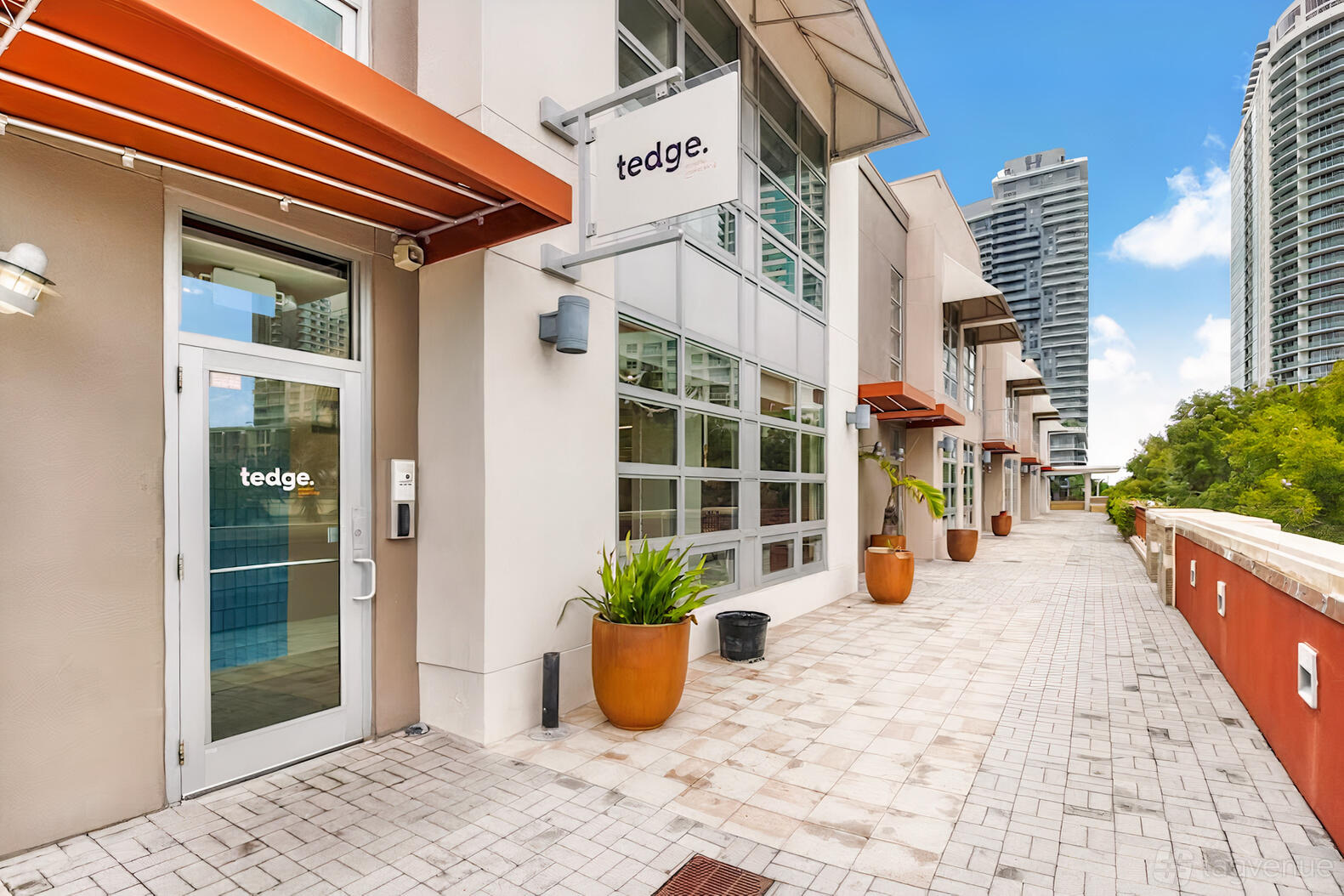 A coworking space with large windows, orange awnings, and potted plants at Tedge Mindful Coworking.