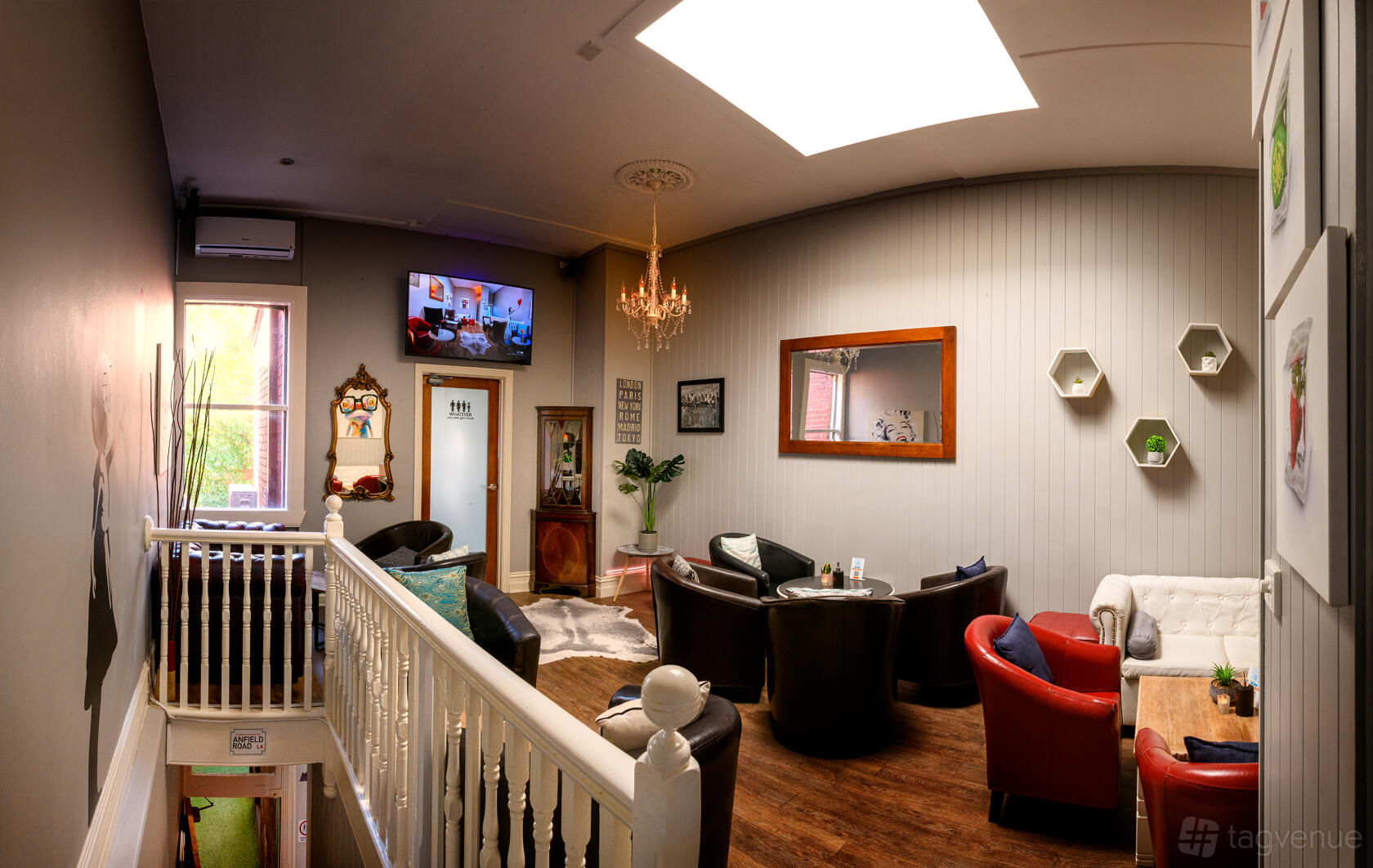 An event loft with armchairs, a chandelier, wood flooring, and wall art at The Tipsy Cow.