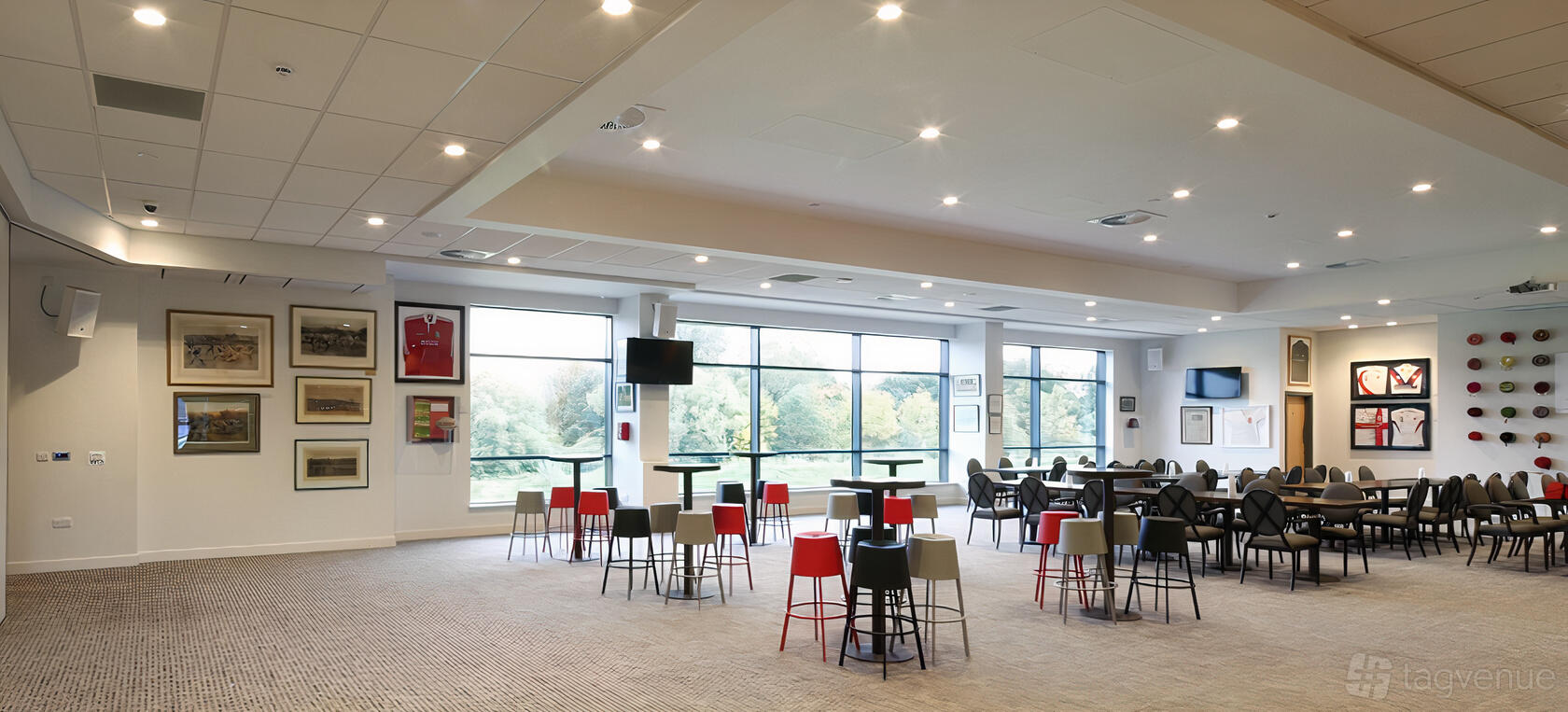 An event space with large windows, high tables with stools, and sports memorabilia on the walls at StoneX Stadium Fez Club.