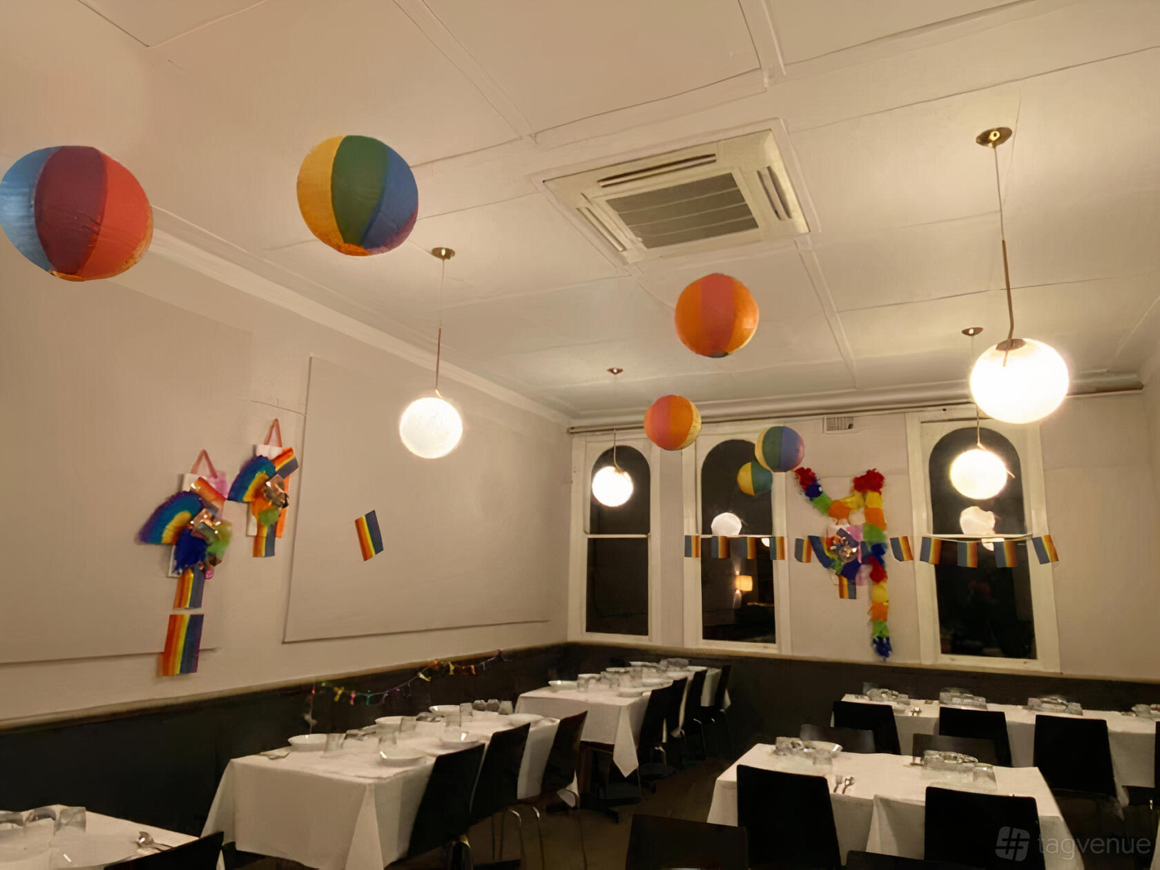 A dining room with rainbow paper lanterns, pride decorations, and round globe lights at Thai Nesia.
