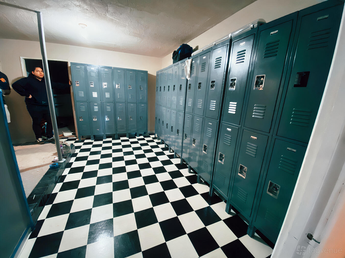 A photo studio locker room with black and white checkered flooring and rows of gray metal lockers at Beam Studio.