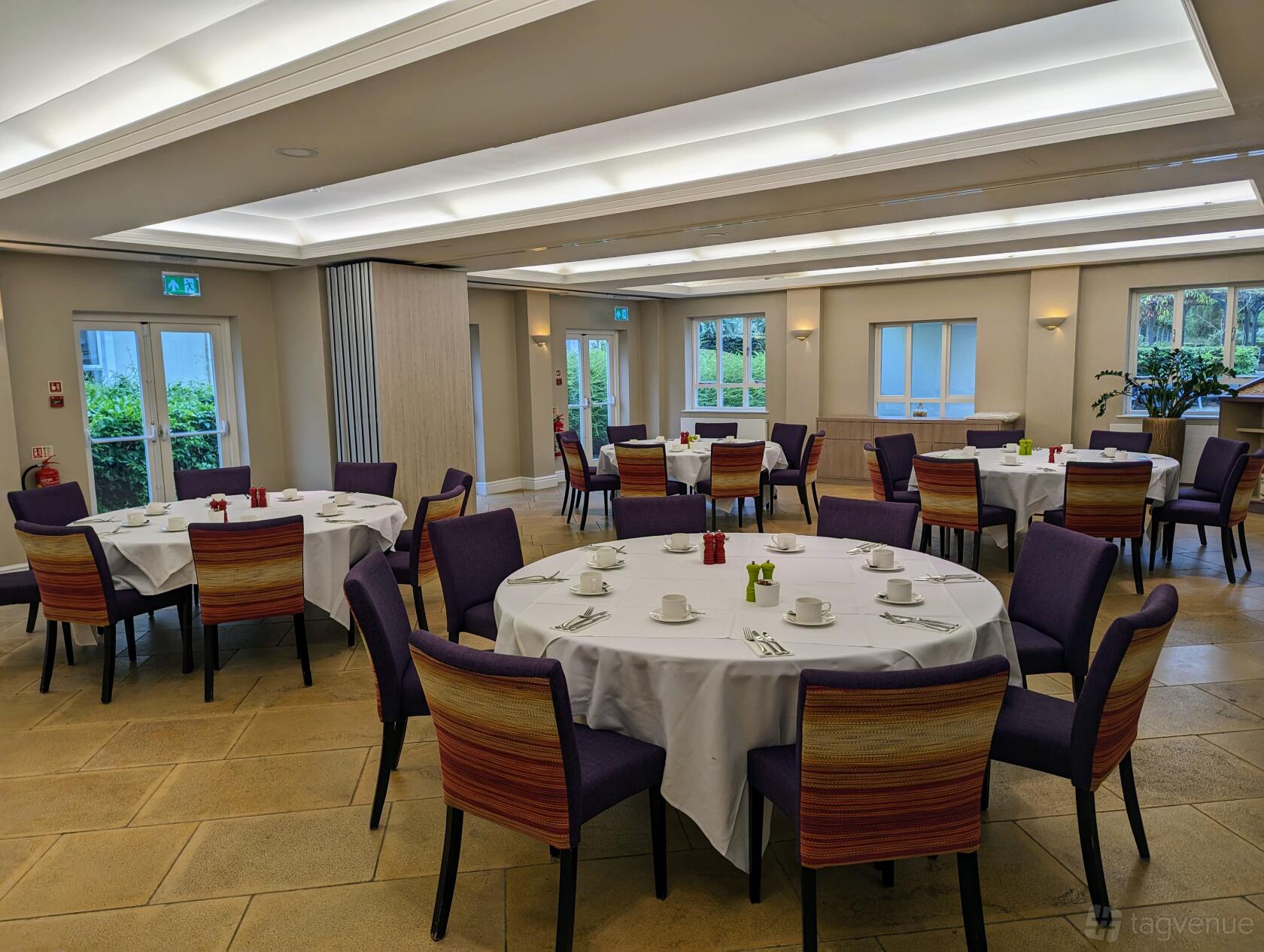 An event space with round tables set with white linens and purple chairs at Sudbury House Hotel