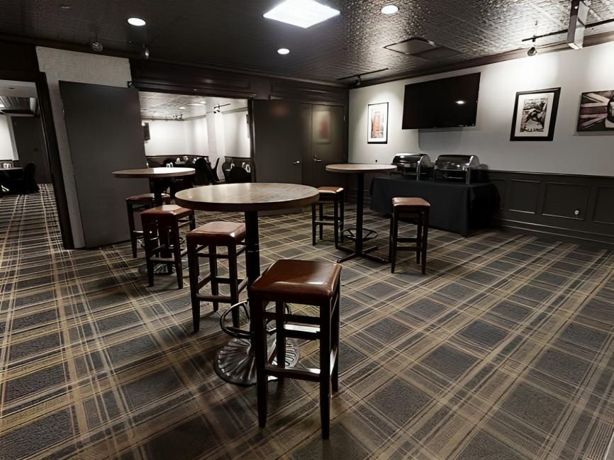A meeting room with round high-top tables, leather barstools, and a wall-mounted TV at Club Quarters Hotel, Chicago, Central Loop.