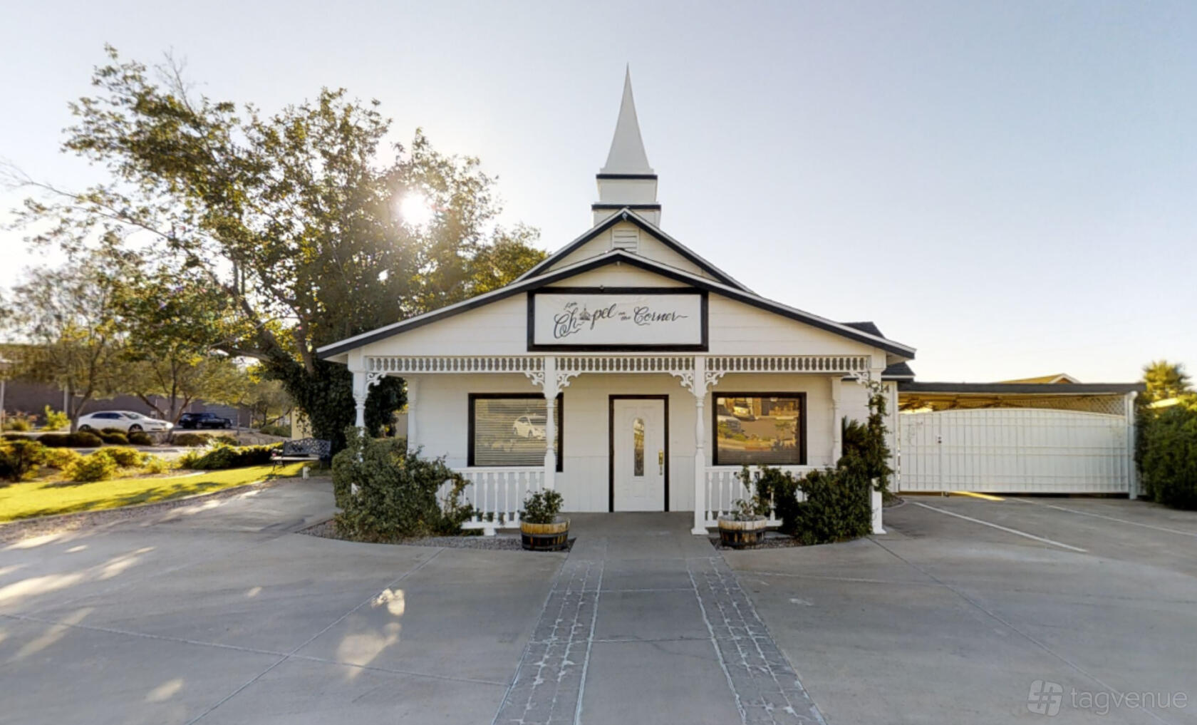 A quaint event space with a white exterior, front porch, and steeple at Little Chapel on the Corner.