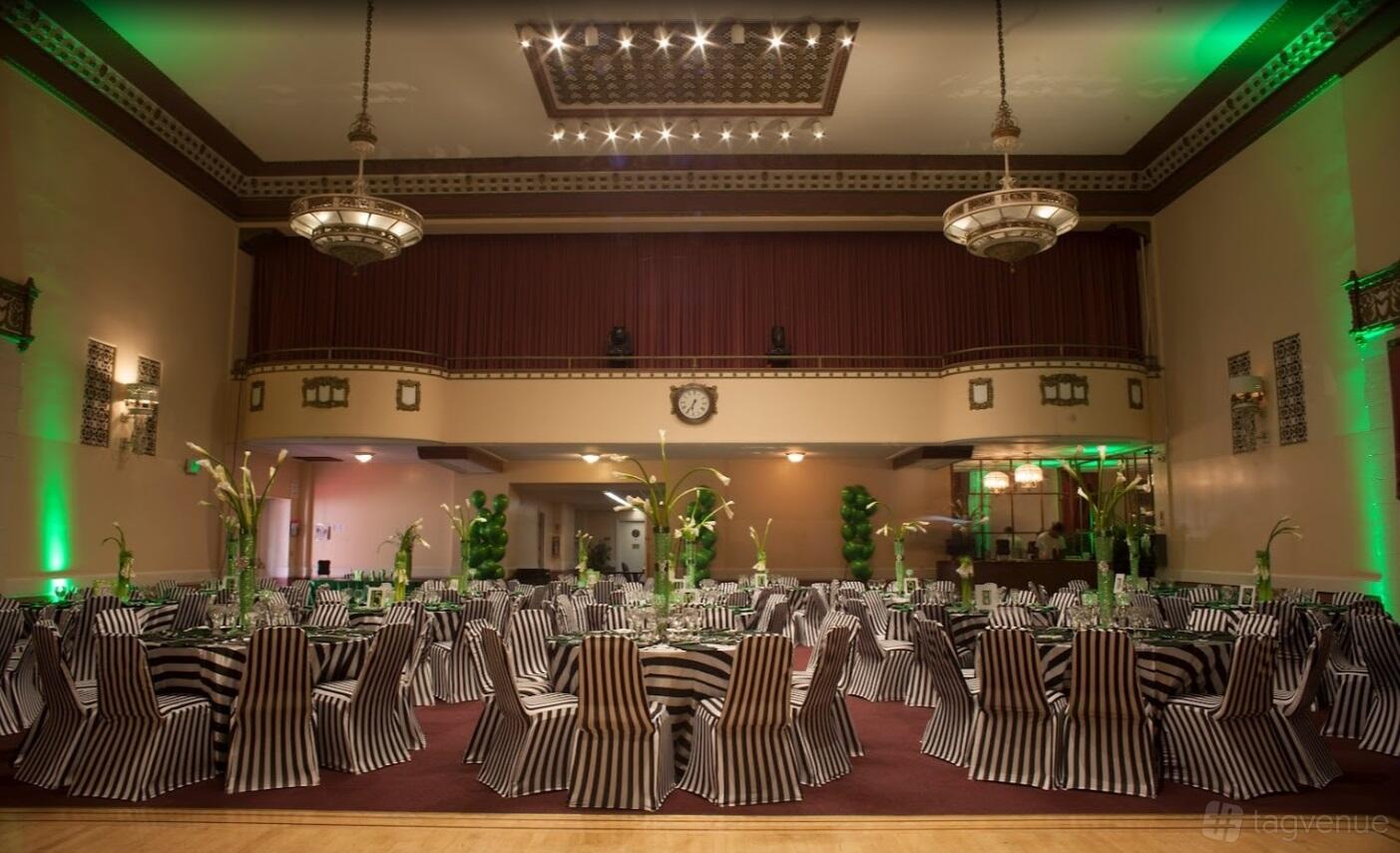 A ballroom with striped chair covers, round tables, and art deco chandeliers at Oakstop Franklin.