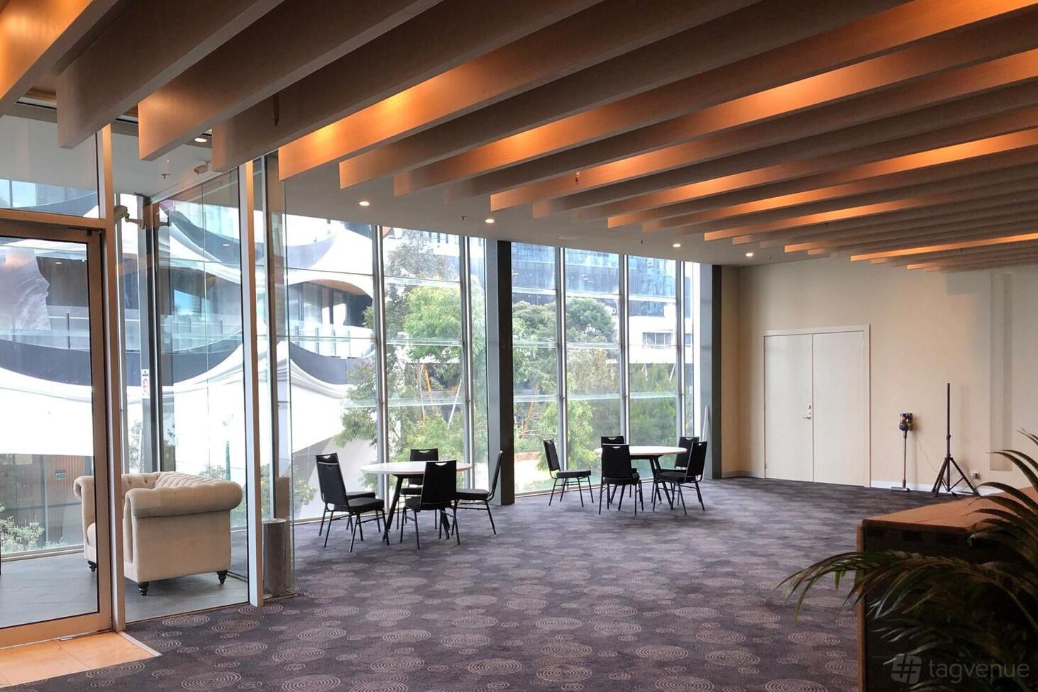 An event venue with floor-to-ceiling windows, exposed beams, and seating areas at The Promenade Docklands.