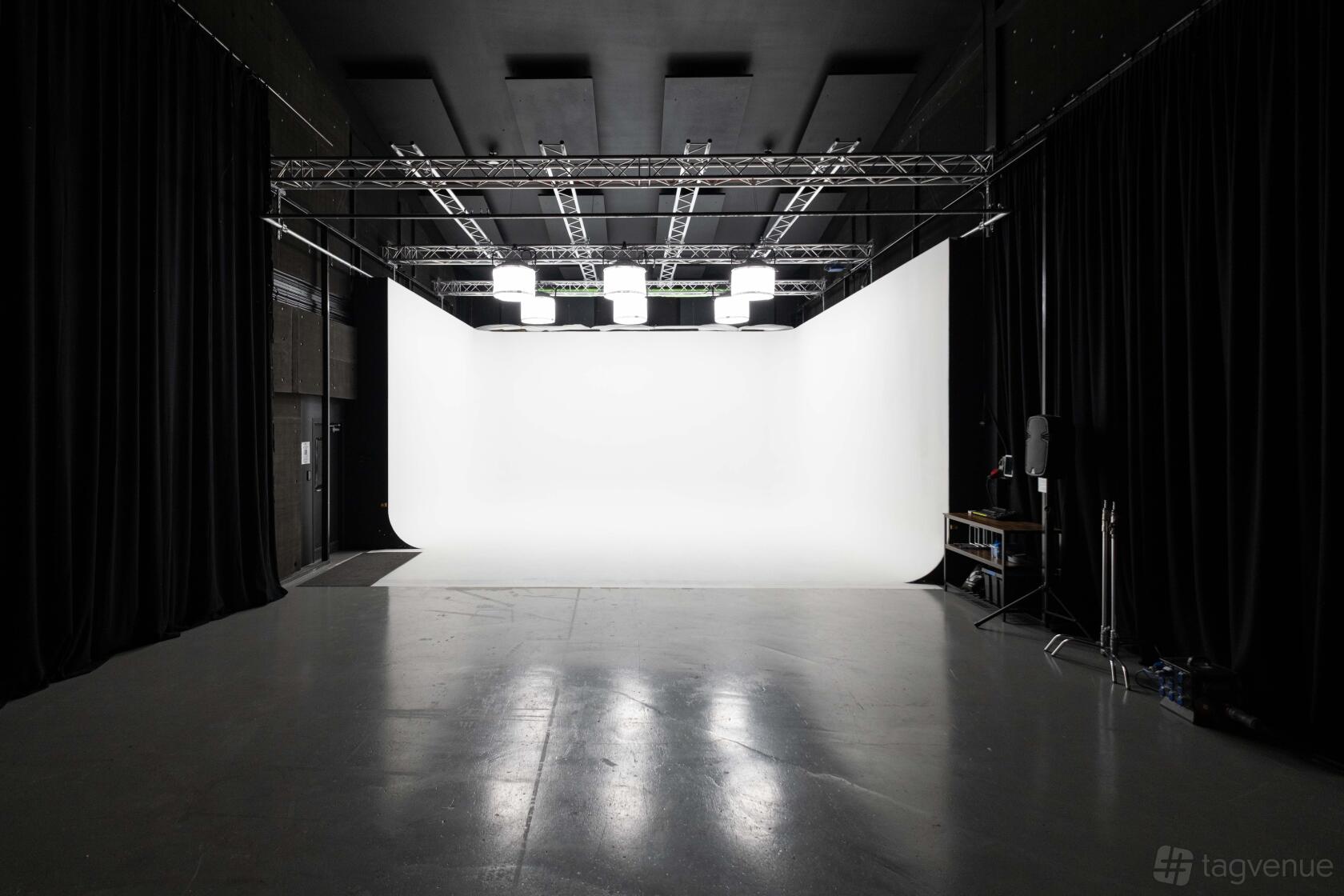 A photo and film studio with a large white cyclorama wall, overhead lighting, and black drapes at Tannery Film Studios.