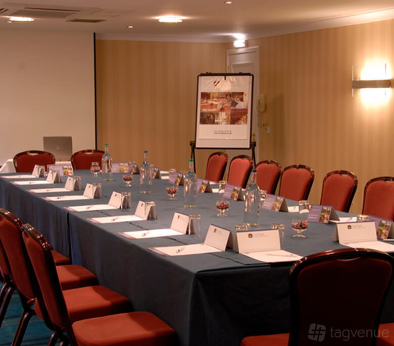 A hotel meeting room with a U-shaped table arrangement, bottled water, and stationery at Keavil House Hotel.