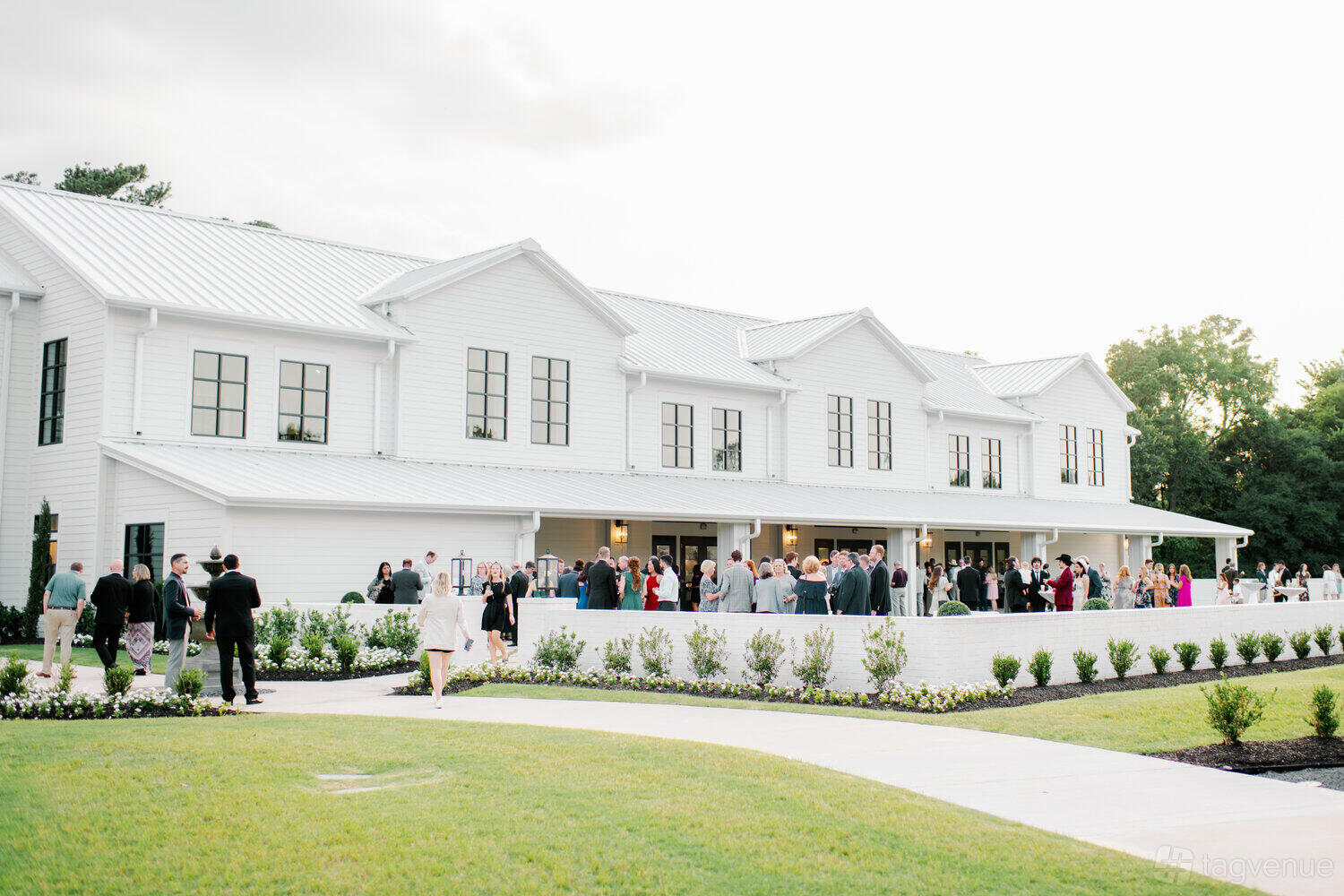 An event venue with a white exterior, large black-trimmed windows, and manicured landscaping at Boxwood Manor.