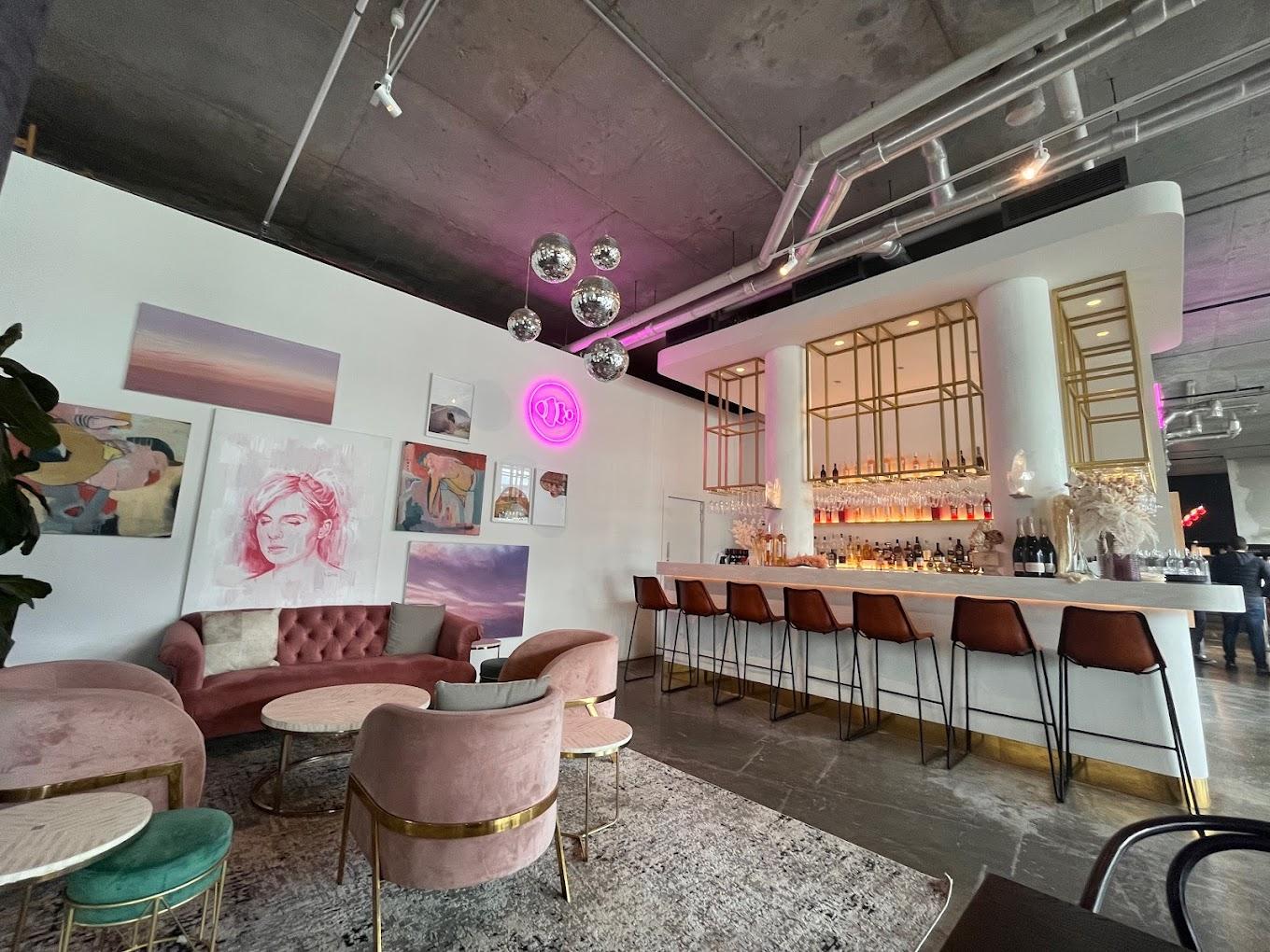 A cafe with velvet lounge seating, round marble tables, and a gold-accented bar at The Espressonist.