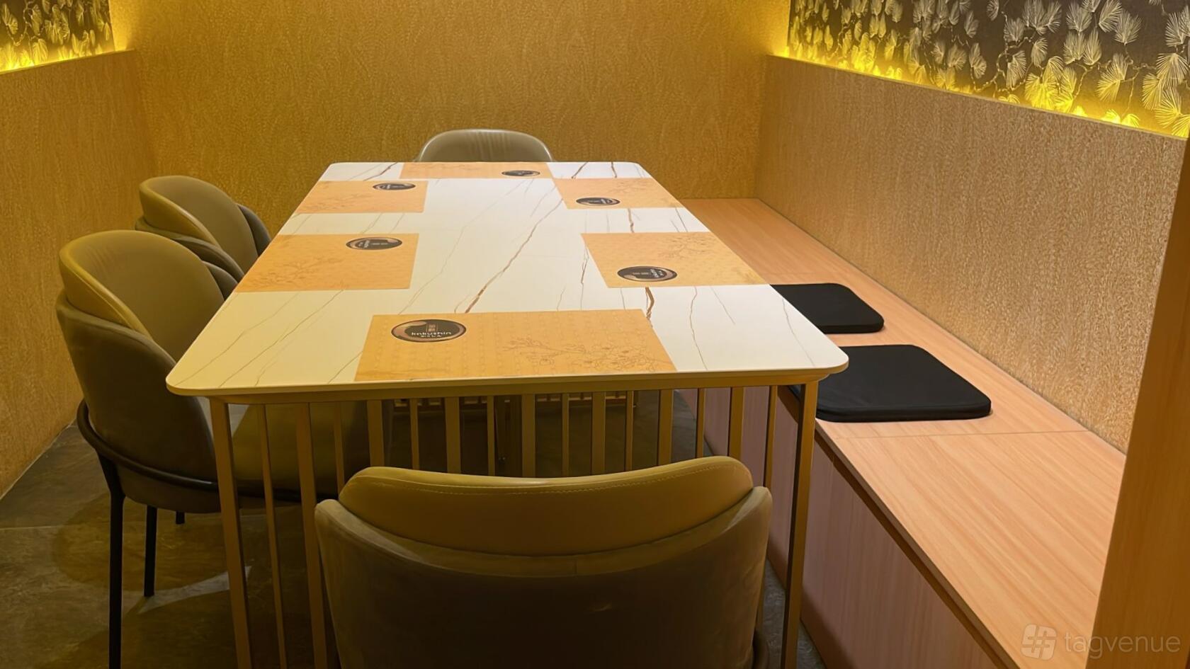 A dining room with a marble table, cushioned chairs, and a textured gold wall at Kakushin.