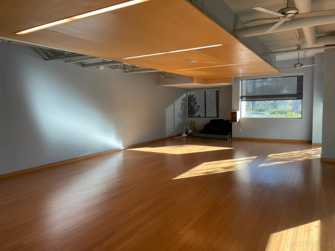 An event space with hardwood floors, natural light, and a wood-paneled ceiling at YogaSix Pasadena.