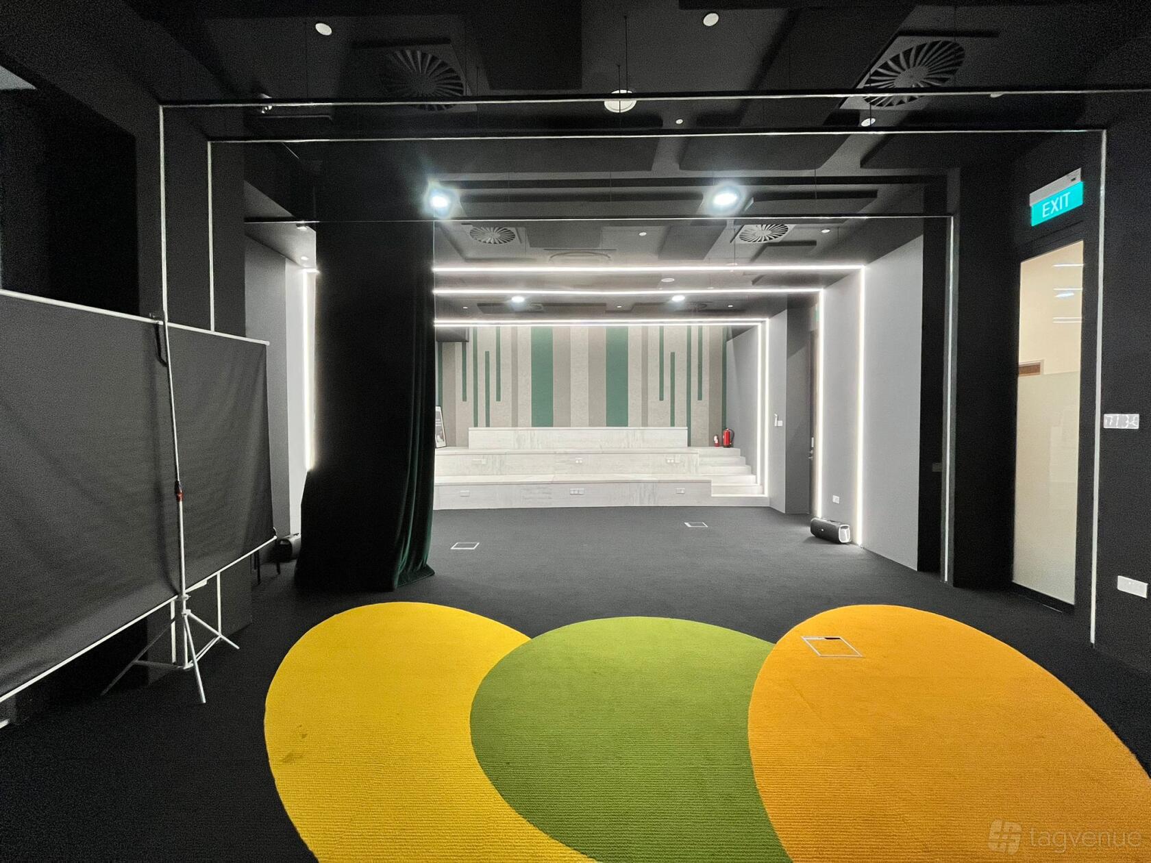 A training room with tiered white seating, geometric wall panels, and colorful carpet accents at Speech Academy Asia.