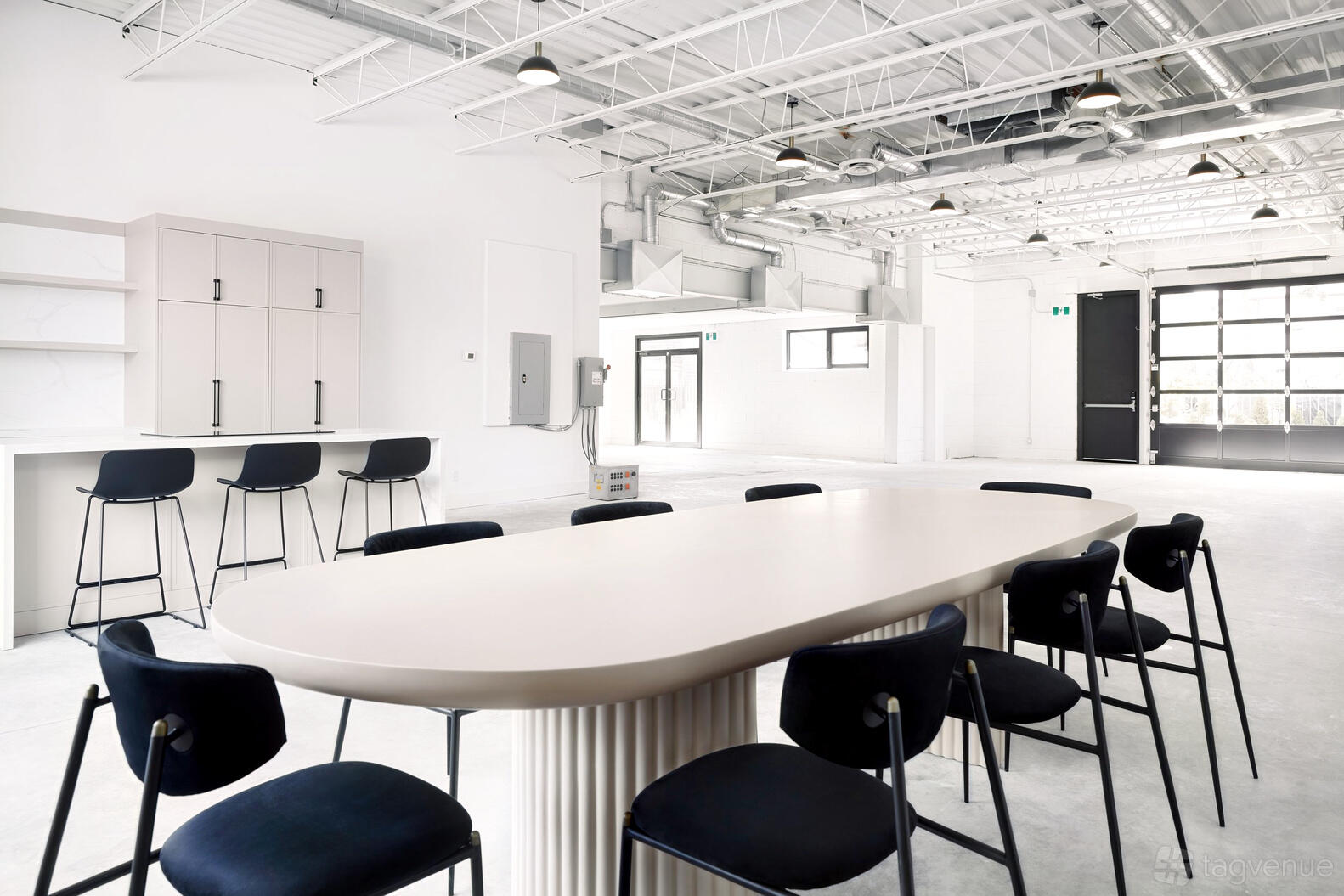 An open studio event space with white walls, high ceilings, and black chairs around an oval table at Album Studios: Mount Dennis.