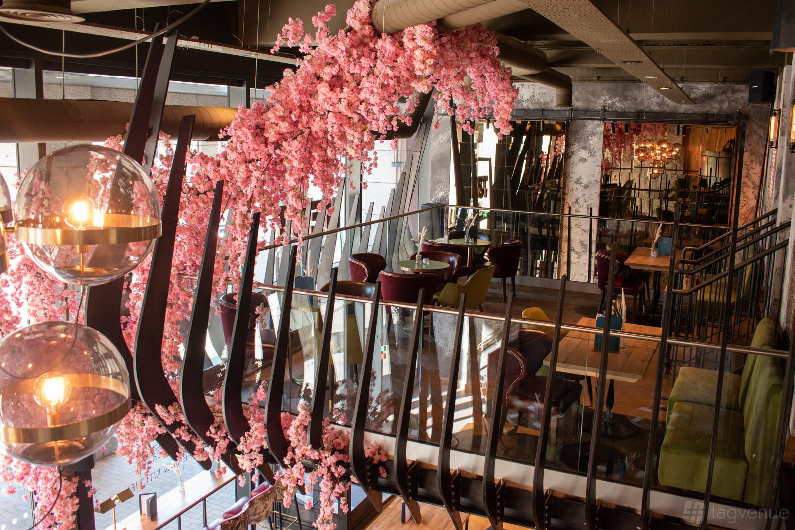 An elevated balcony with pink floral décor, floor-to-ceiling windows, and hanging globe lights at NEST BISHOPSGATE.