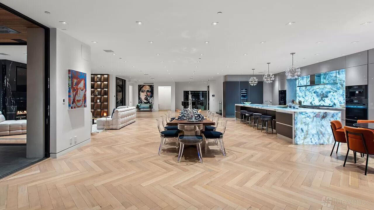 An event venue with herringbone wood floors, long dining table, open kitchen, and modern art at Modern Contemporary Compound.