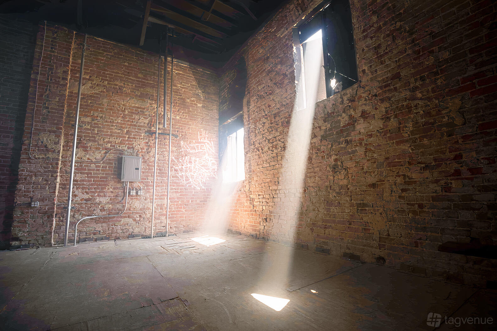 A photo studio with exposed brick walls, high ceilings, and sunlight beaming through windows at Beam Studio.