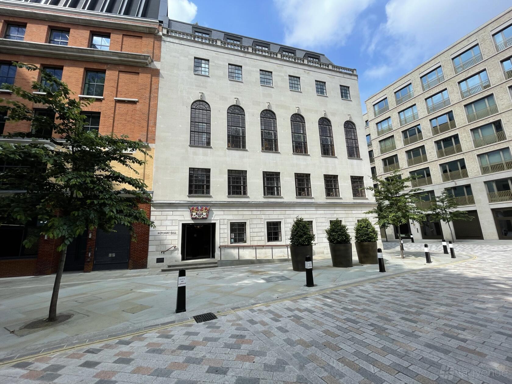 A historic building with arched windows, stone facade, and crest above the entrance at 87 Barts Close.