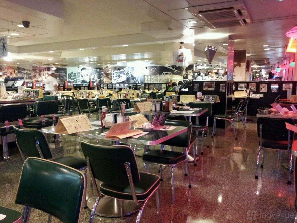 A restaurant with green vinyl chairs, chrome-edged tables, checkered floors, and retro decor at Mel's Drive-In 4TH & MISSION.