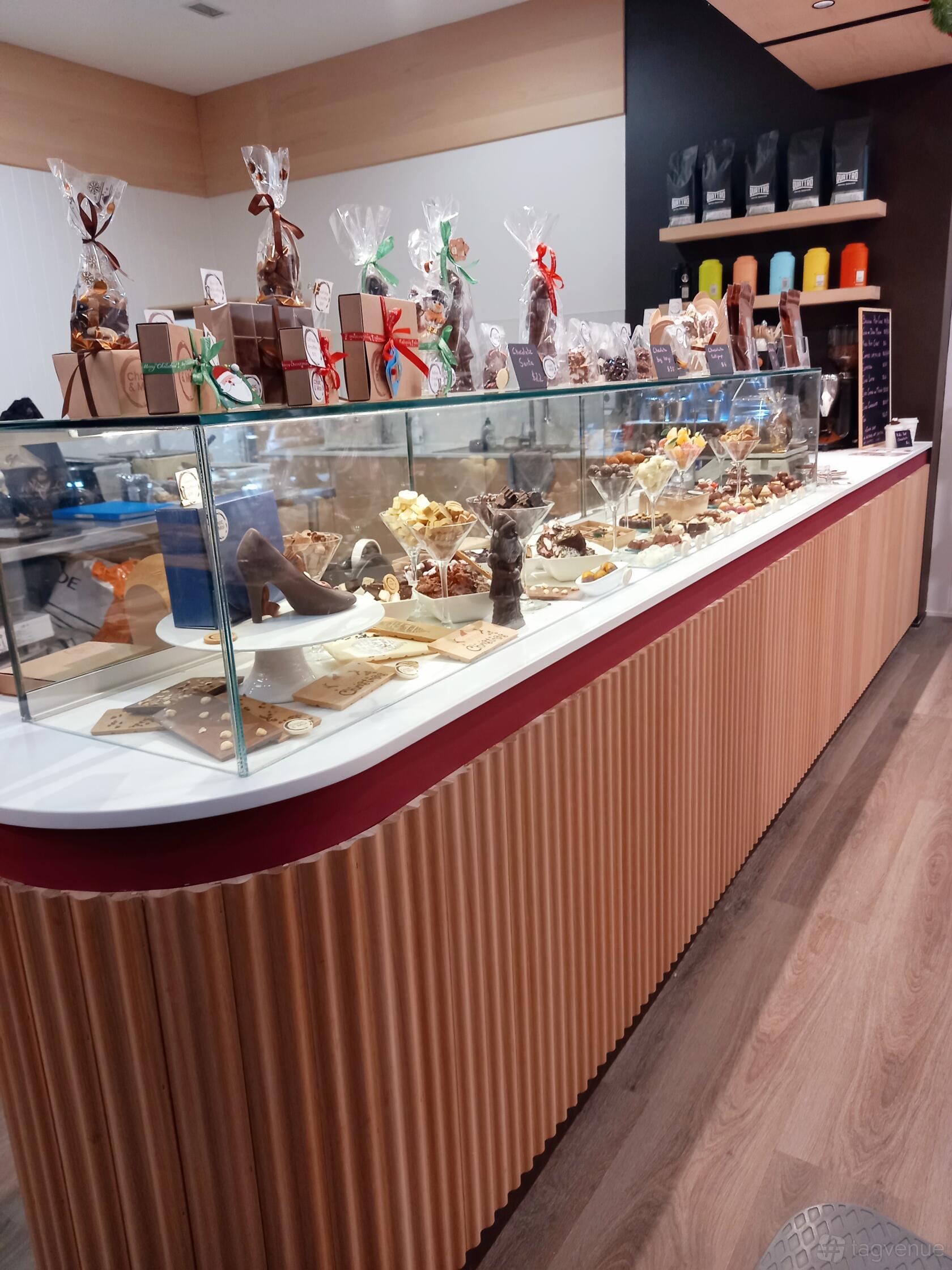 A cafe with a glass display case featuring assorted chocolates and confections at Choc & Moi.