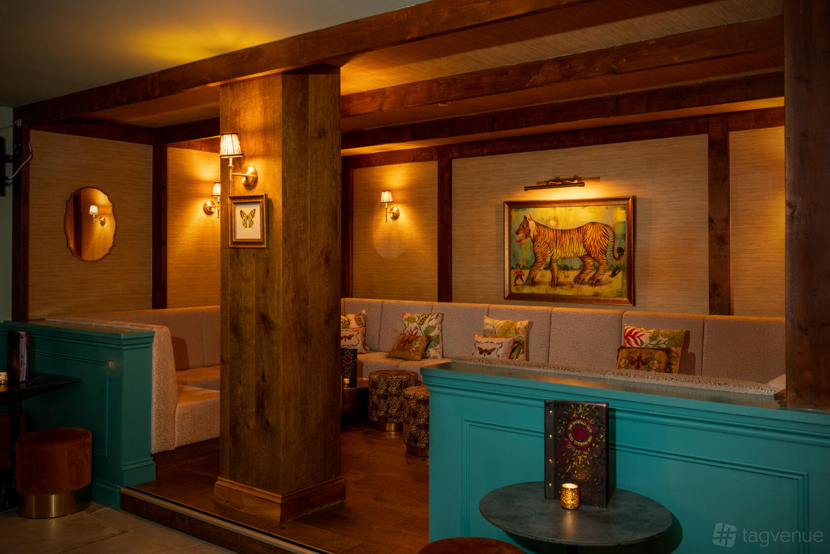 A semi-private lounge with wood beams, patterned pillows, and warm lighting at The Cocktail Club Birmingham.