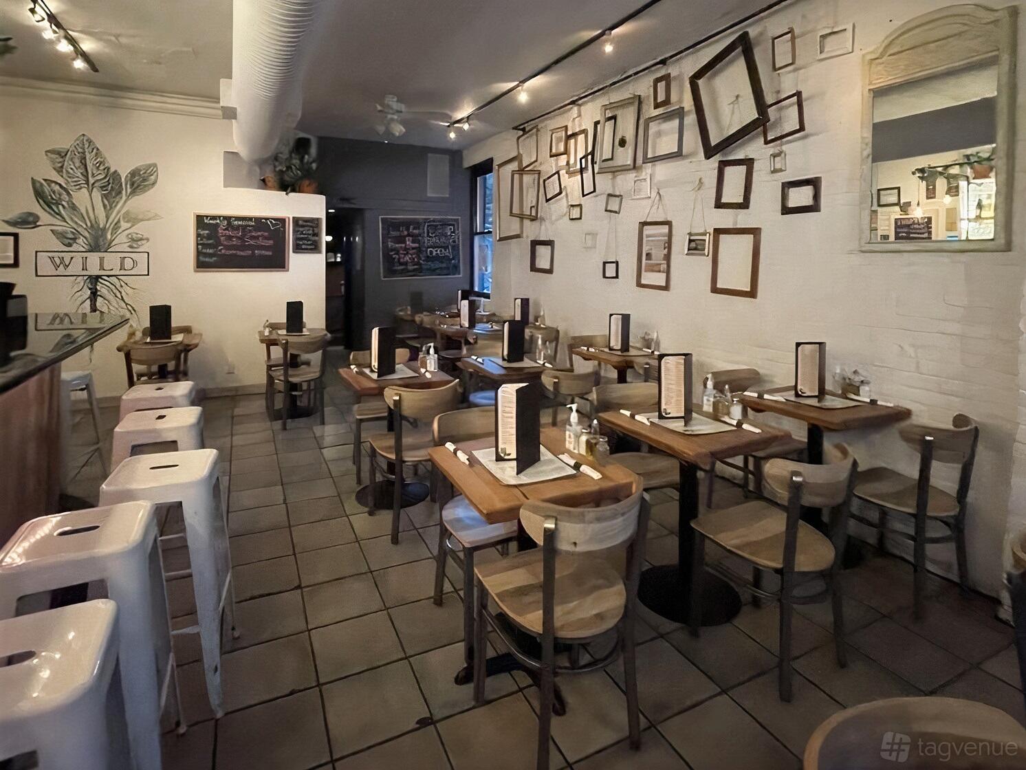 A restaurant with wooden tables, metal chairs, and an accent wall decorated with empty picture frames at Wild Park Slope.