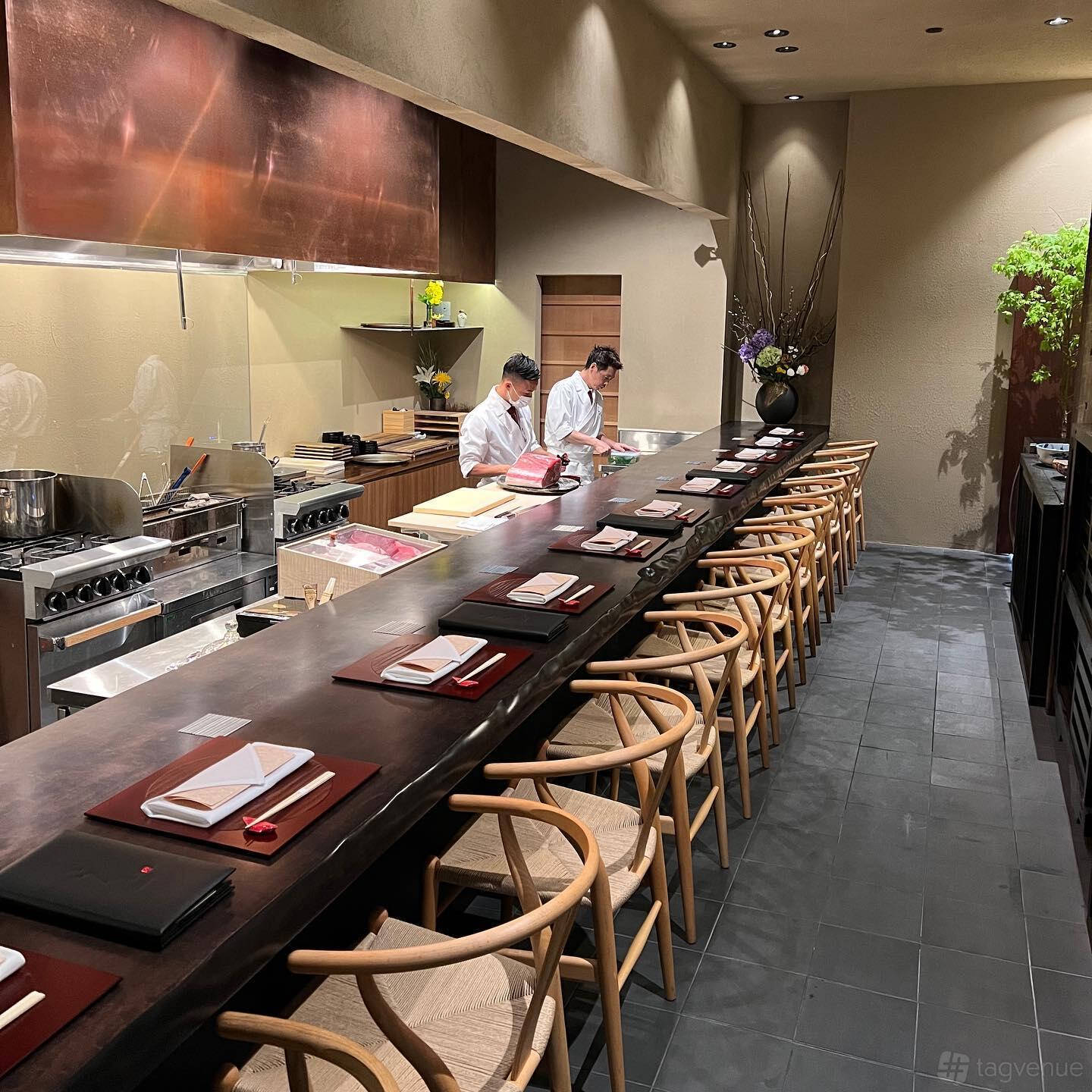 A restaurant with an open kitchen, long wooden counter seating, and chef-prepared dishes at KAISEKI SANGA.