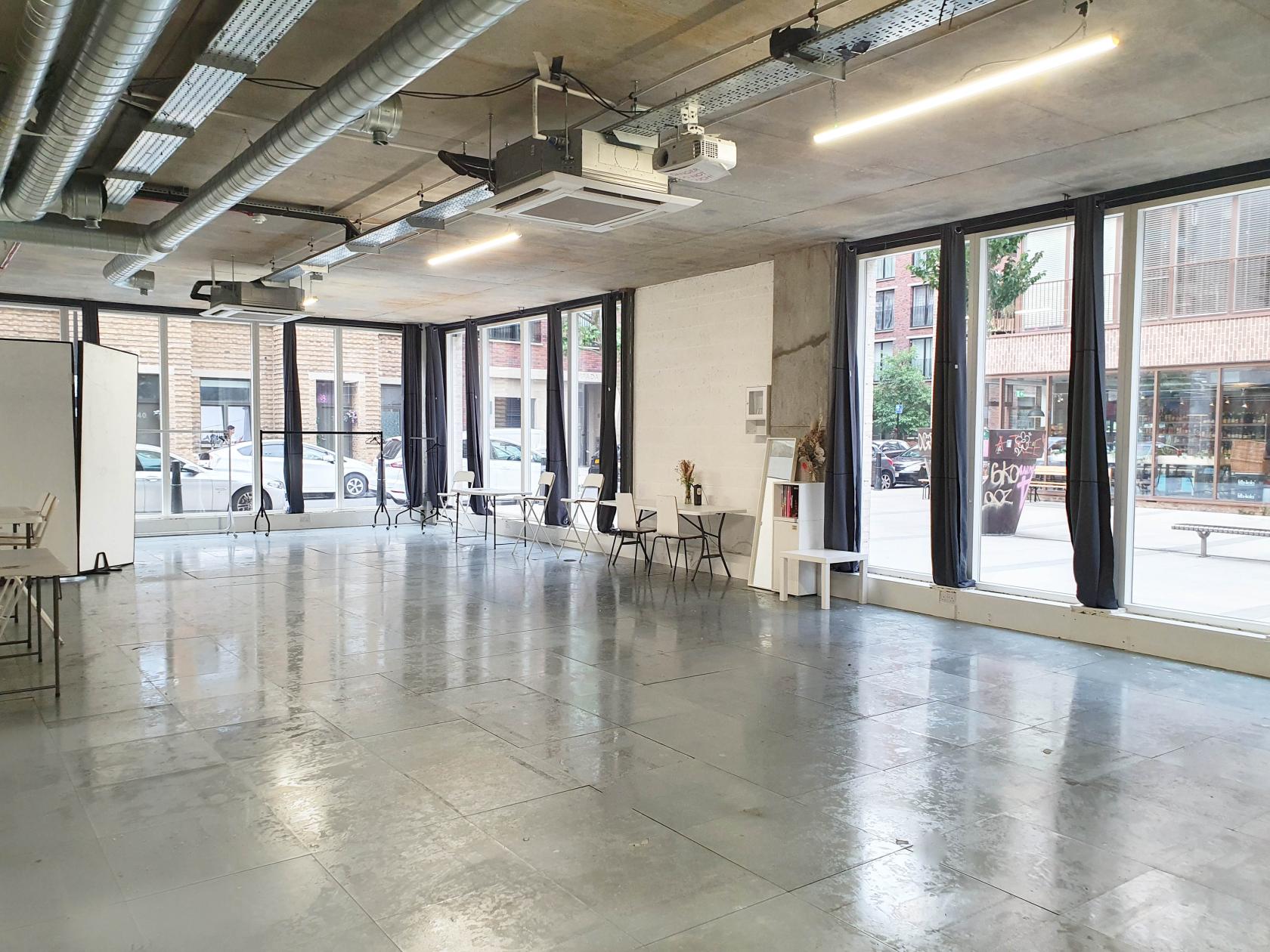 A photo studio with floor-to-ceiling windows, polished concrete floors, and exposed ductwork at Indra Gallery.