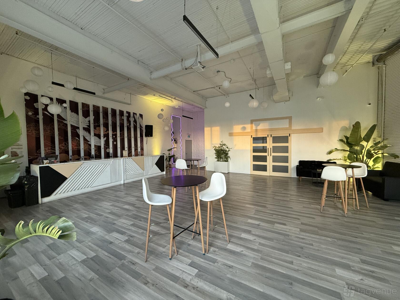 An event space with high ceilings, light wood floors, modern pendant lights, and a bar at Roll This Way.