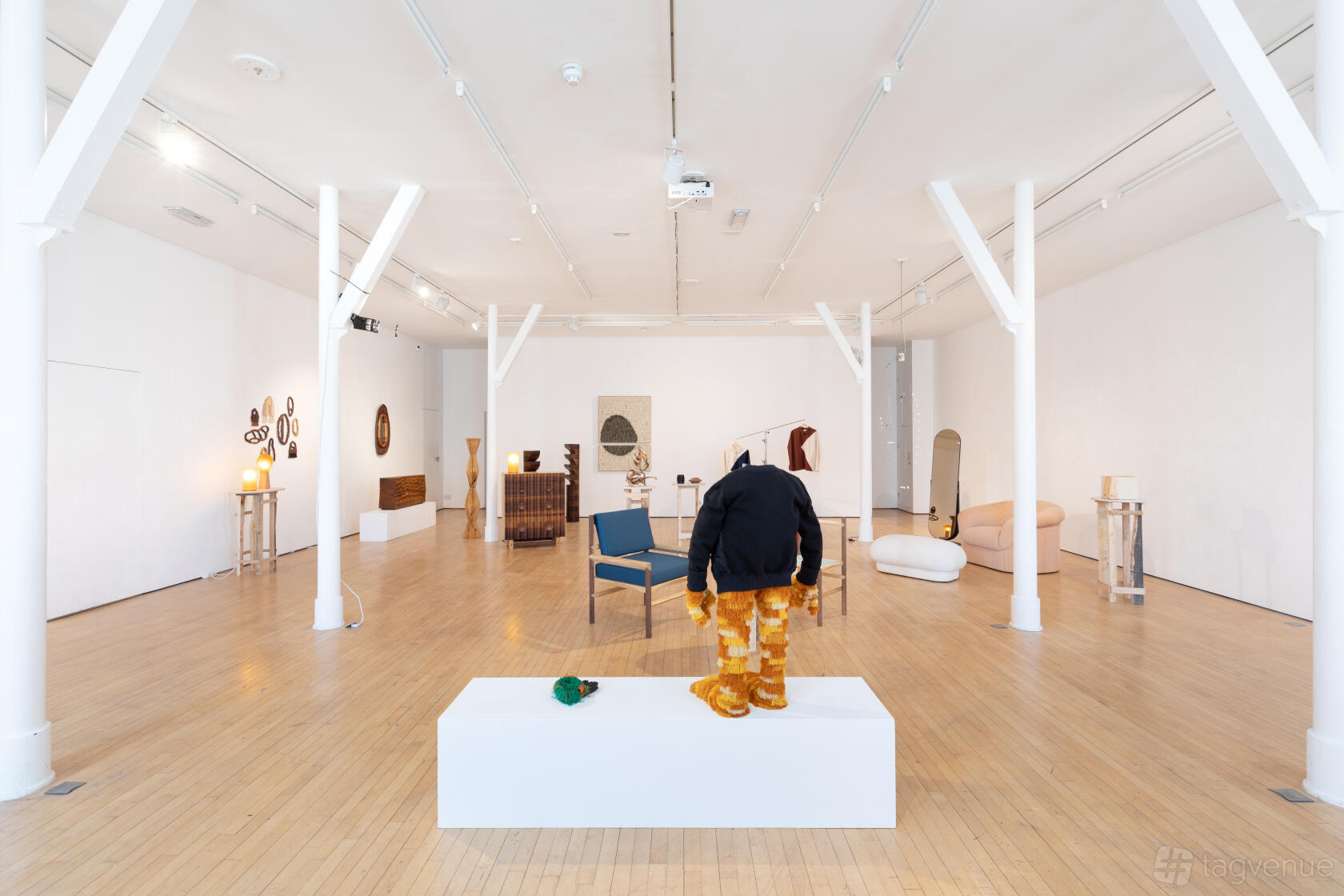 A gallery with white walls, wooden floors, and contemporary sculptures and furniture displays at PS49.
