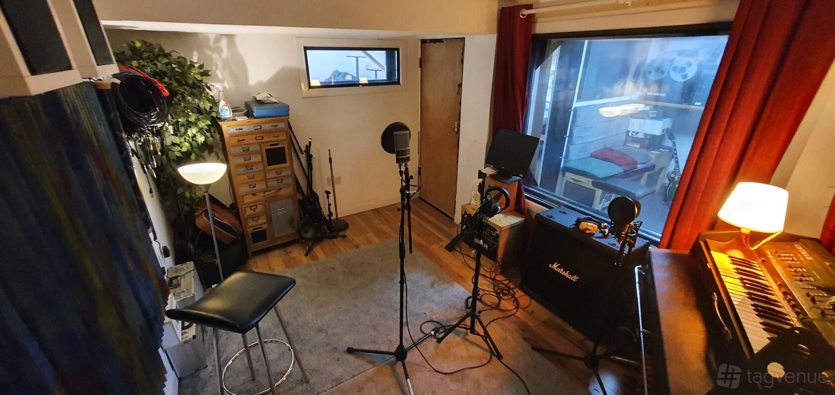 A recording studio with microphones, amplifiers, and soundproof windows at HQ Recording Studio.