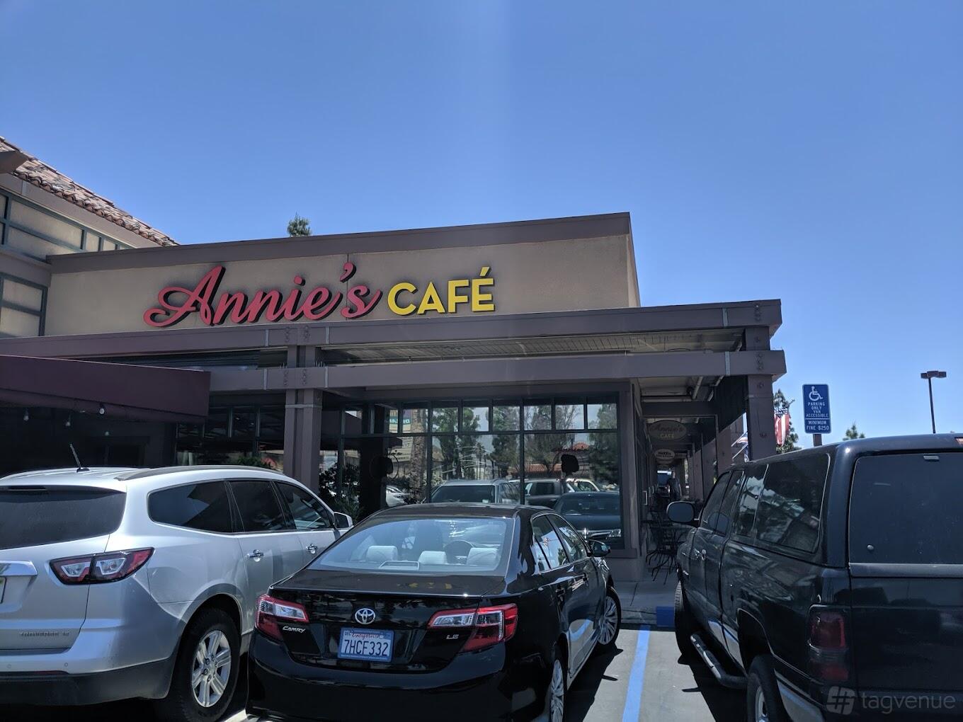 A café with a large storefront sign, glass entrance, and adjacent parking lot at Annie's Cafe Lake Elsinore.