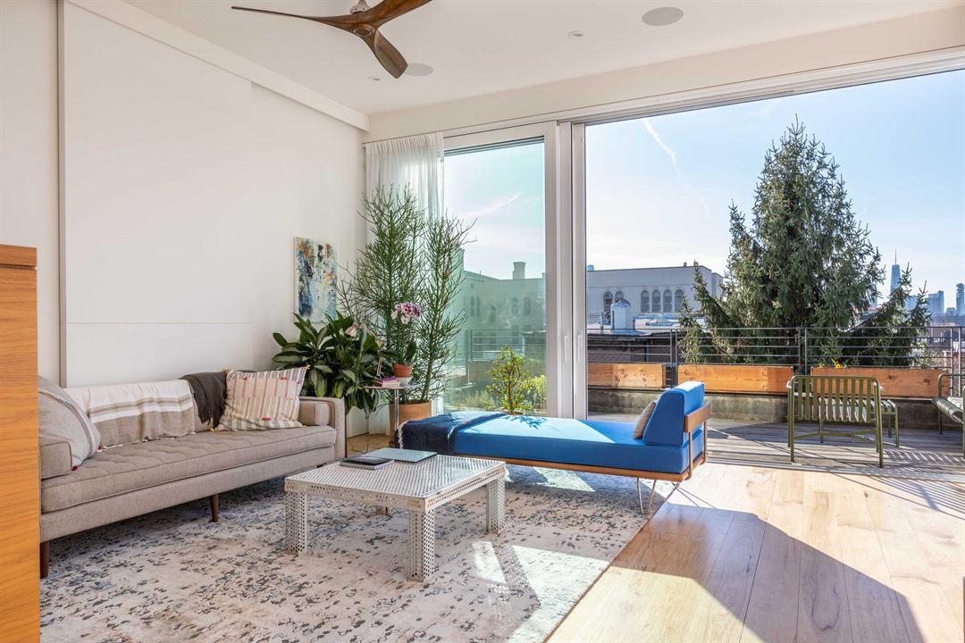 An apartment living area with floor-to-ceiling windows, light wood floors, and access to a terrace at Casa Caeli.