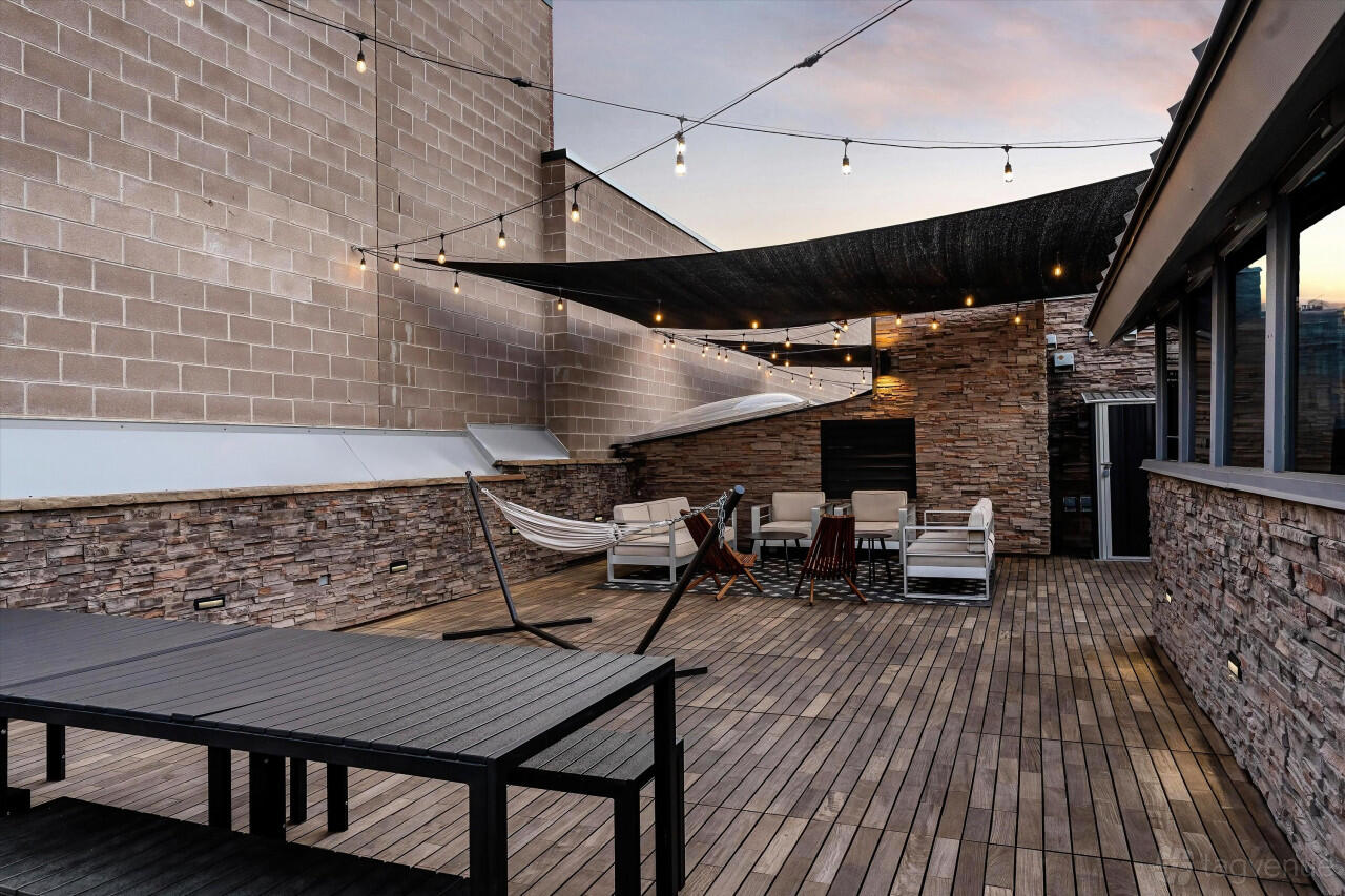 An event terrace with string lights, hammocks, and lounge seating on wooden decking at Hotel Residential of Denver.